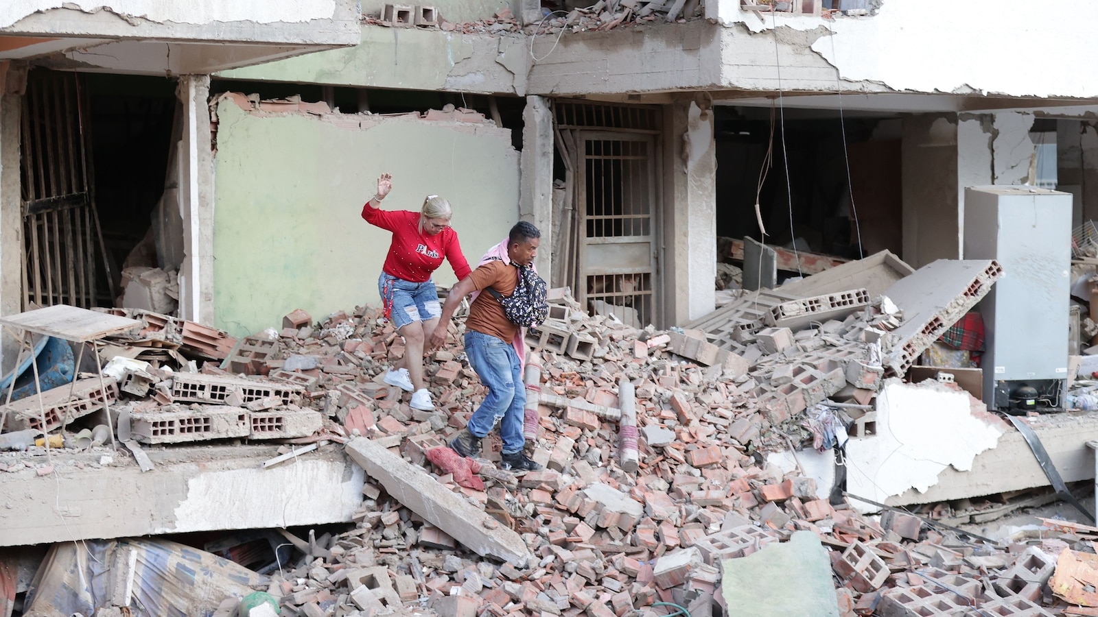 Residents walk through the rubble of damaged apartment buildings following the twin 7.2 and 7.5-magnitude earthquakes that struck the country, in Catia la Mar, Venezuela, June 25, 2026. 