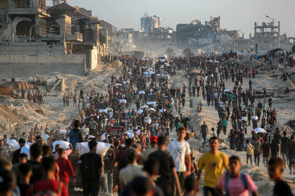 PHOTO: People carrying sacks of flour walk along al-Rashid street in western Jabalia, June 17, 2025