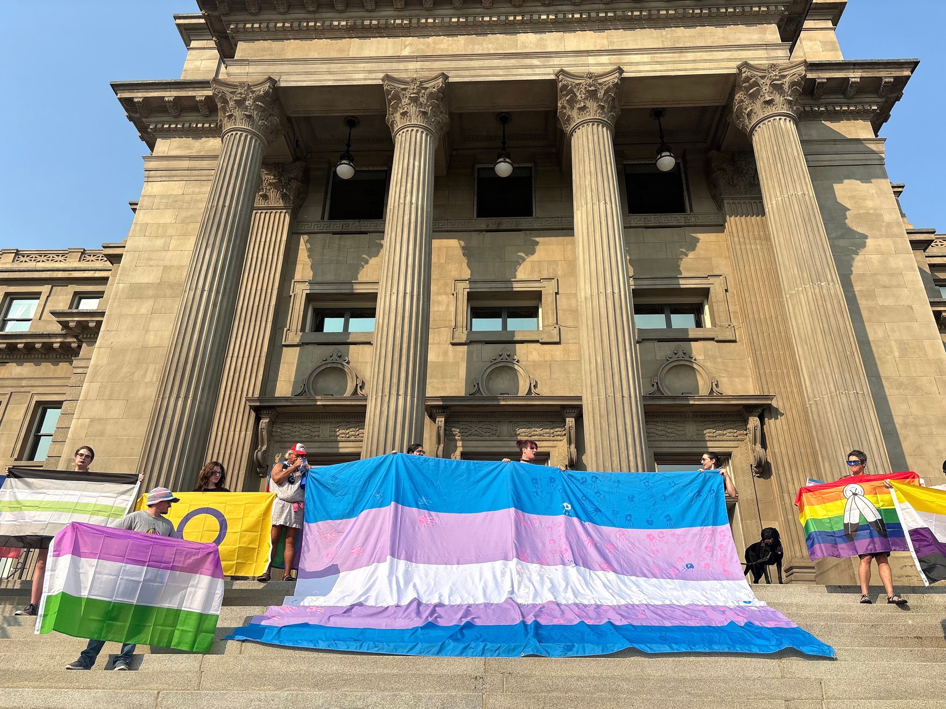 PHOTO: Volunteers display the Trans Pride flag and other flags on the steps of the Idaho Capitol on Sept. 5, 2025, for the Boise Trans March.