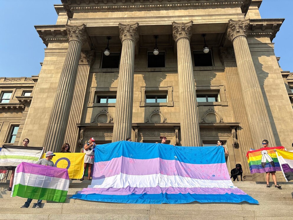 PHOTO: Volunteers display the Trans Pride flag and other flags on the steps of the Idaho Capitol on Sept. 5, 2025, for the Boise Trans March. 