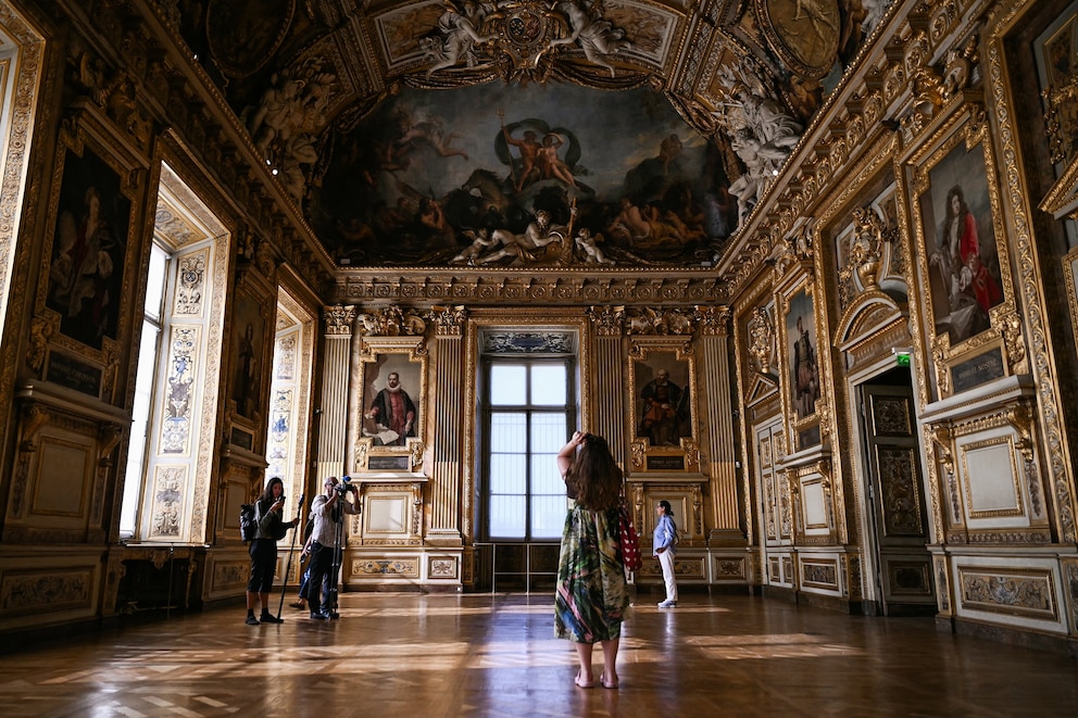 PHOTO: Visitors take a picture of the window which was broken during the reopening to the public of the Apollo Gallery, where French crown jewels were stolen in a 2025 heist, at the Musee du Louvre in Paris on July 22, 2026.