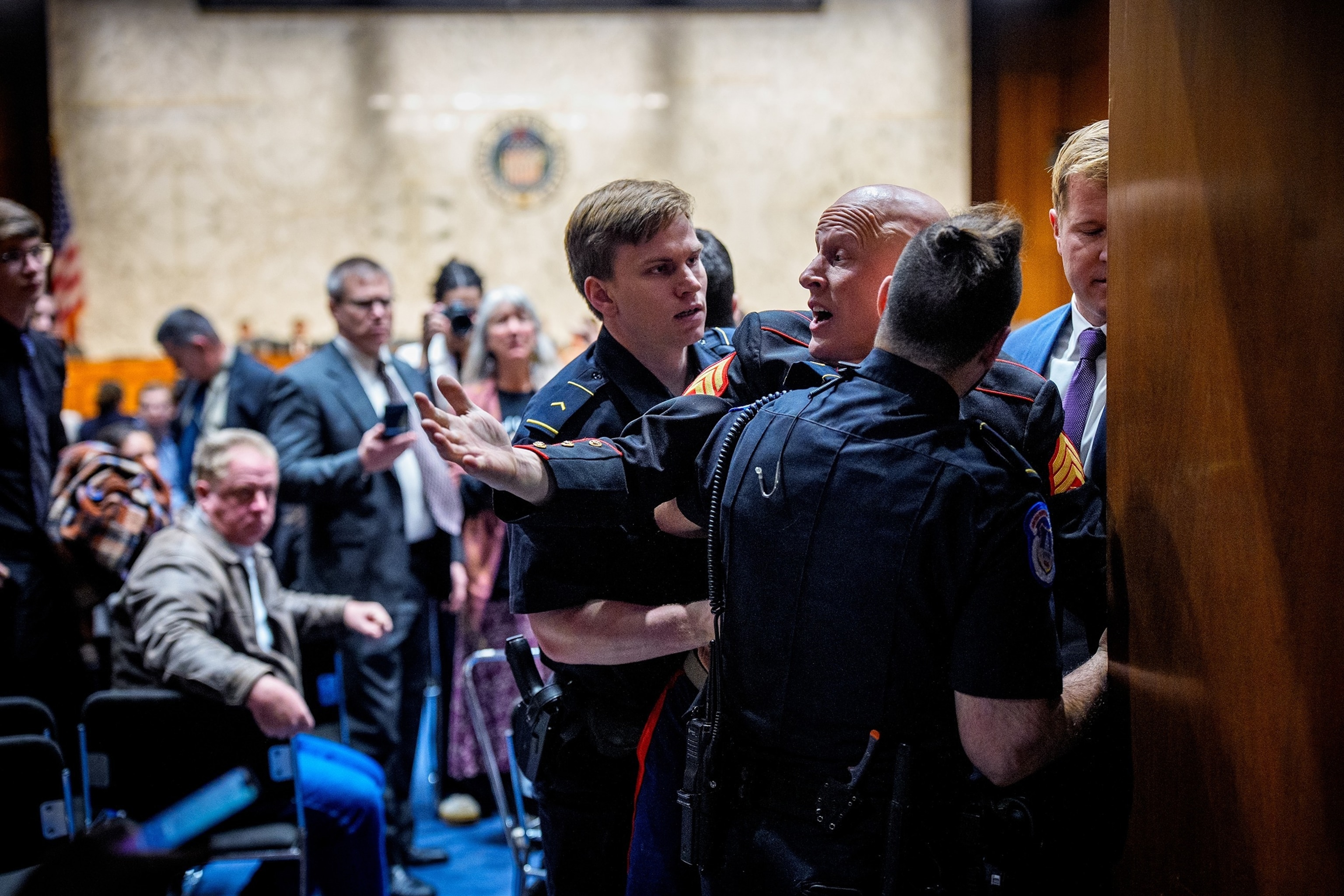 PHOTO: A protester dressed in a military uniform gets stuck in a door, injuring his arm, as Sen. Tim Sheehy and Capitol Police officers attempt to remove him from a Senate Armed Services Subcommittee hearing on Capitol Hill on March 4, 2026 in Washington.