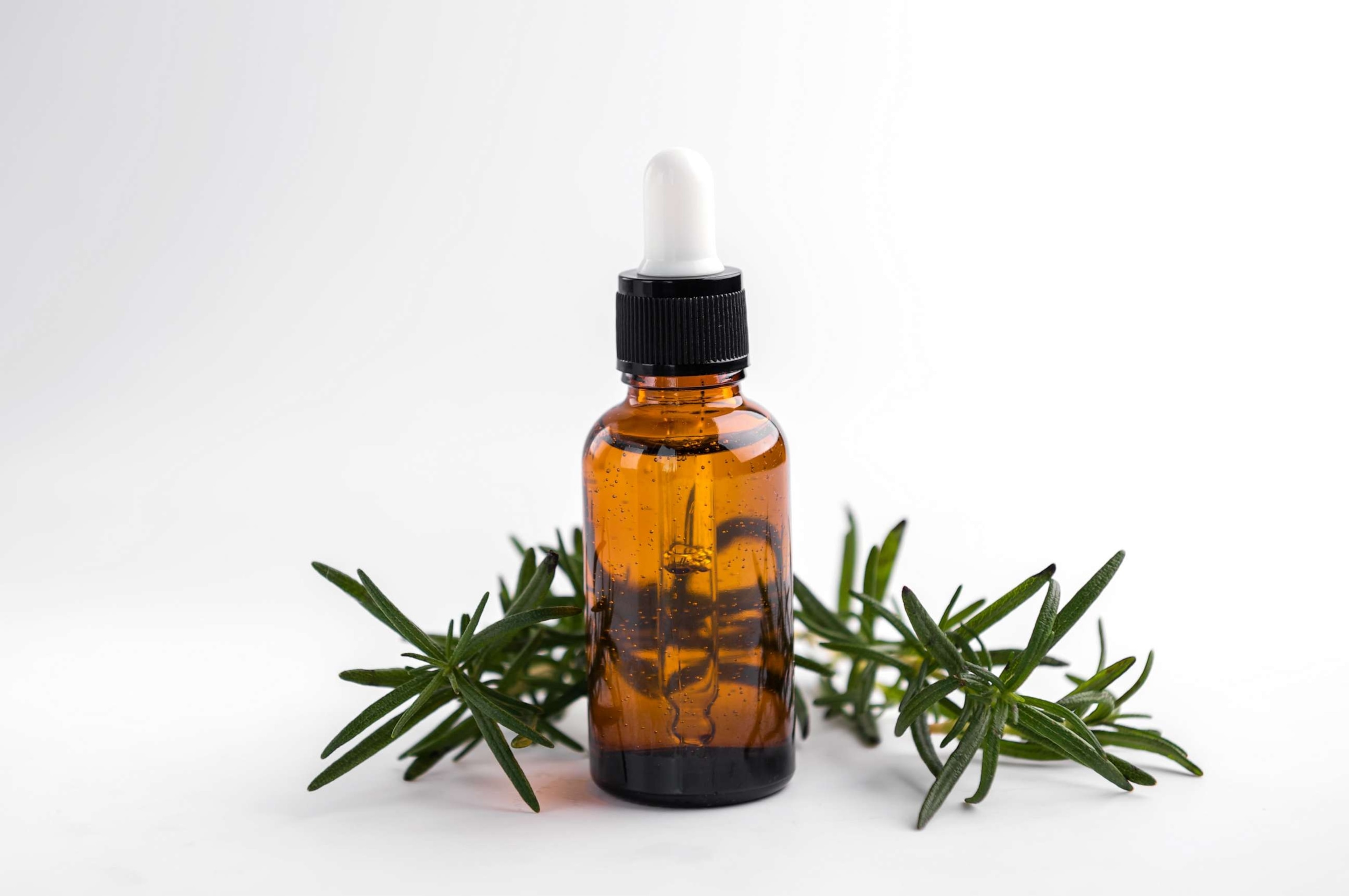 PHOTO: Rosemary oil bottle on white background.