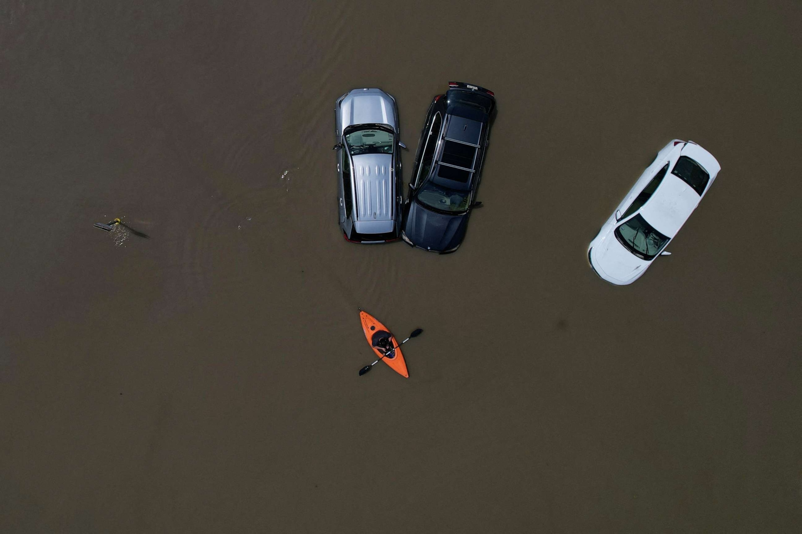 PHOTO: A person in a canoe passes parked cars partially submerged by floodwaters from recent rainstorms in Montpelier, Vermont, on July 11, 2023.