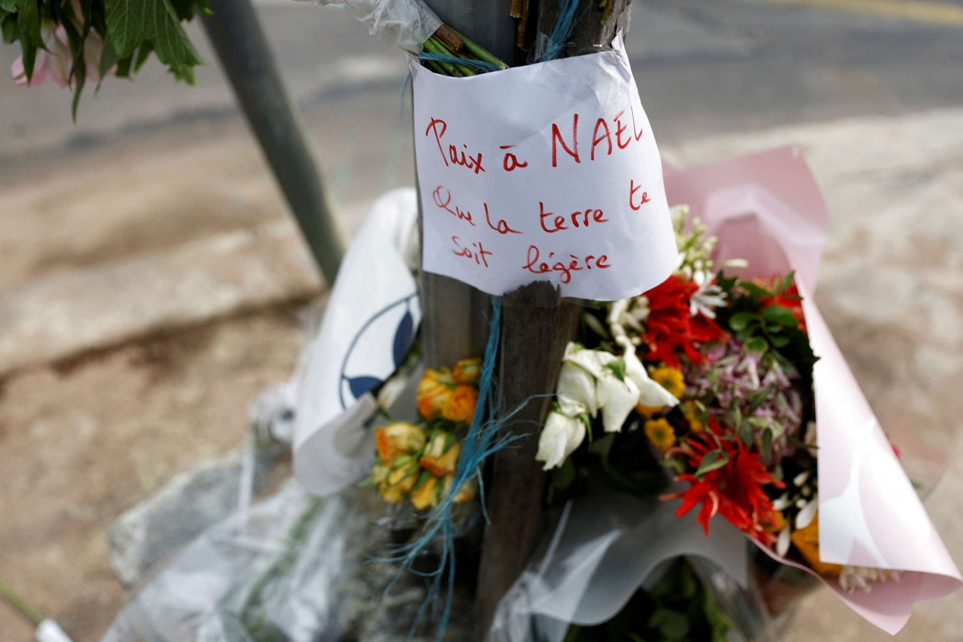 PHOTO: Flowers are seen at the site where 17-year-old Nahel M. was shot and killed by a police officer in Nanterre, a suburb of Paris, France, on June 29, 2023. The message reads "Peace to Nael, may the earth be light to you."