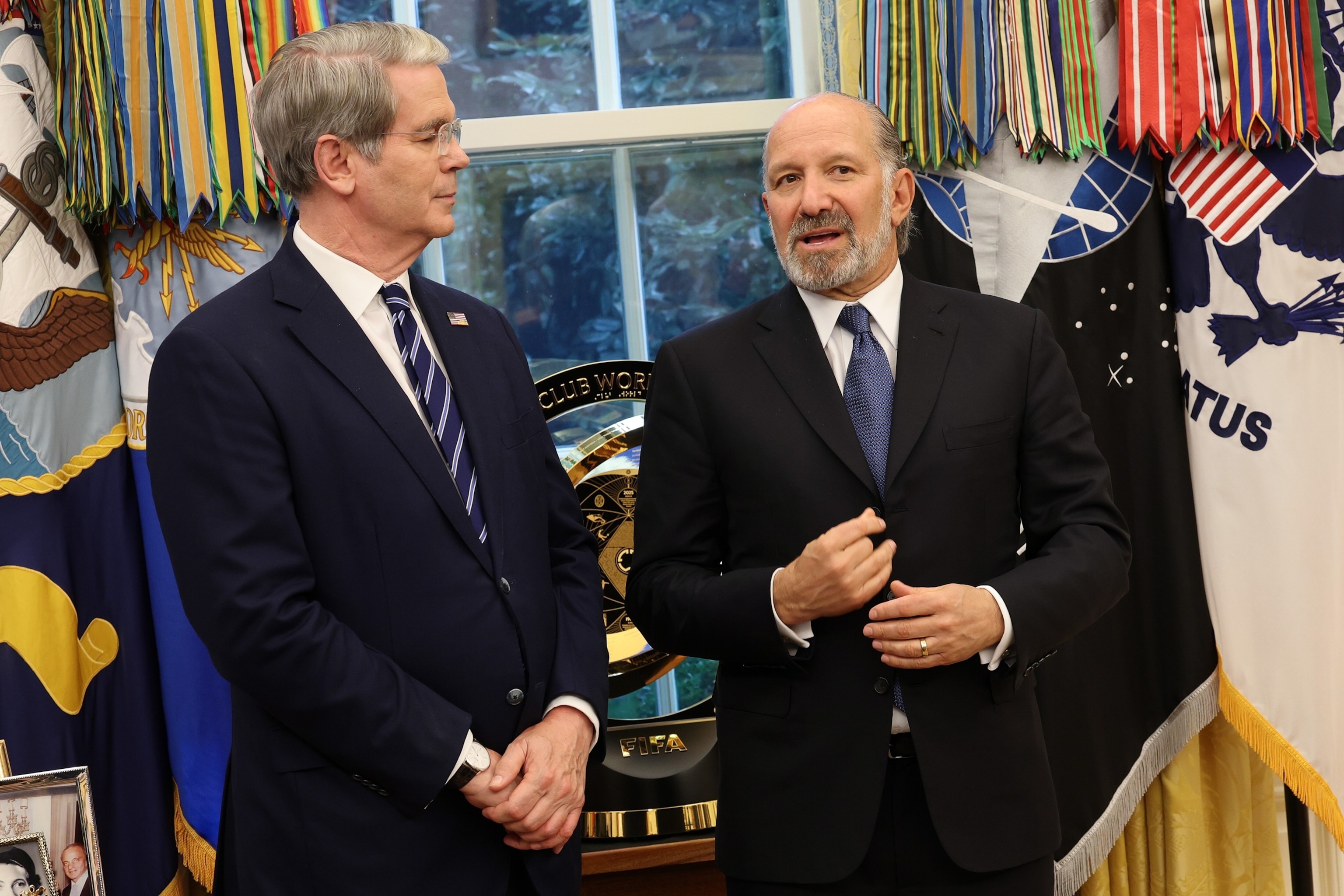 PHOTO: Treasury Secretary Scott Bessent speaks with Secretary of Commerce Howard Lutnick prior to an event with President Donald Trump and Apple CEO Tim Cook in the Oval Office of the White House, Aug. 6, 2025 in Washington.
