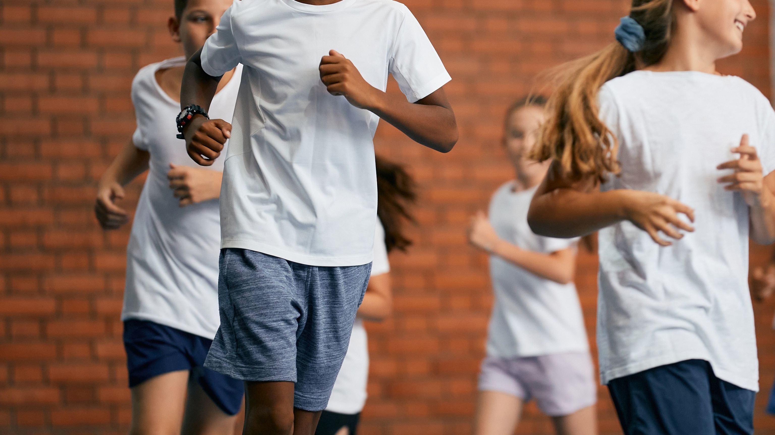 PHOTO: Multi-ethnic group of school children run during physical education class at school gym.