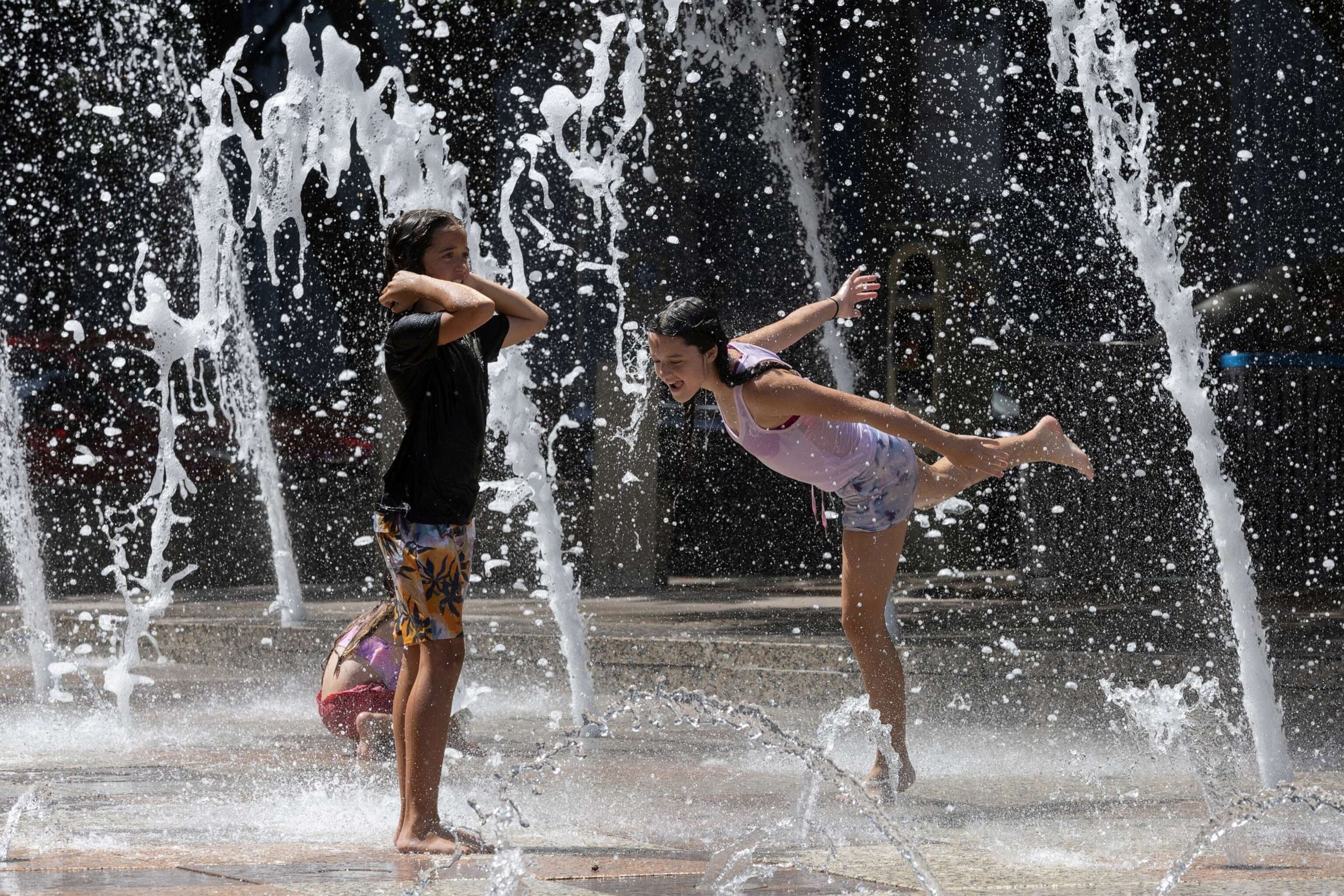 PHOTO: Sisters Olivia, 10, and Evelyn Black, 12, play in Gateway Fountains at Discovery Green park to escape the hot weather in Houston, Texas, July 18, 2023.