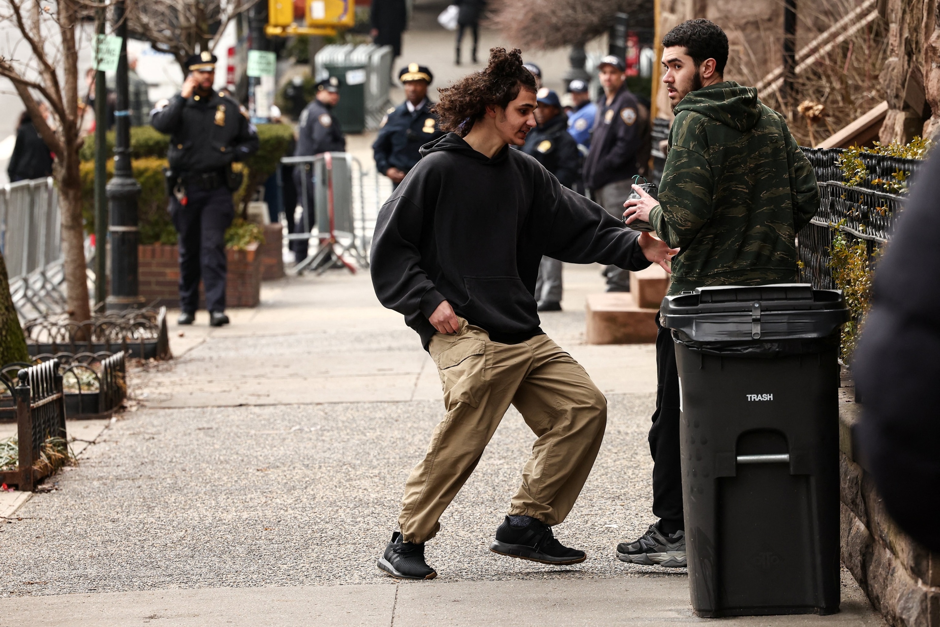 PHOTO: An activist is handed a homemade explosive device by a fellow activist before throwing it towards police during a protest in front of Gracie Mansion, on March 7, 2026, in New York.