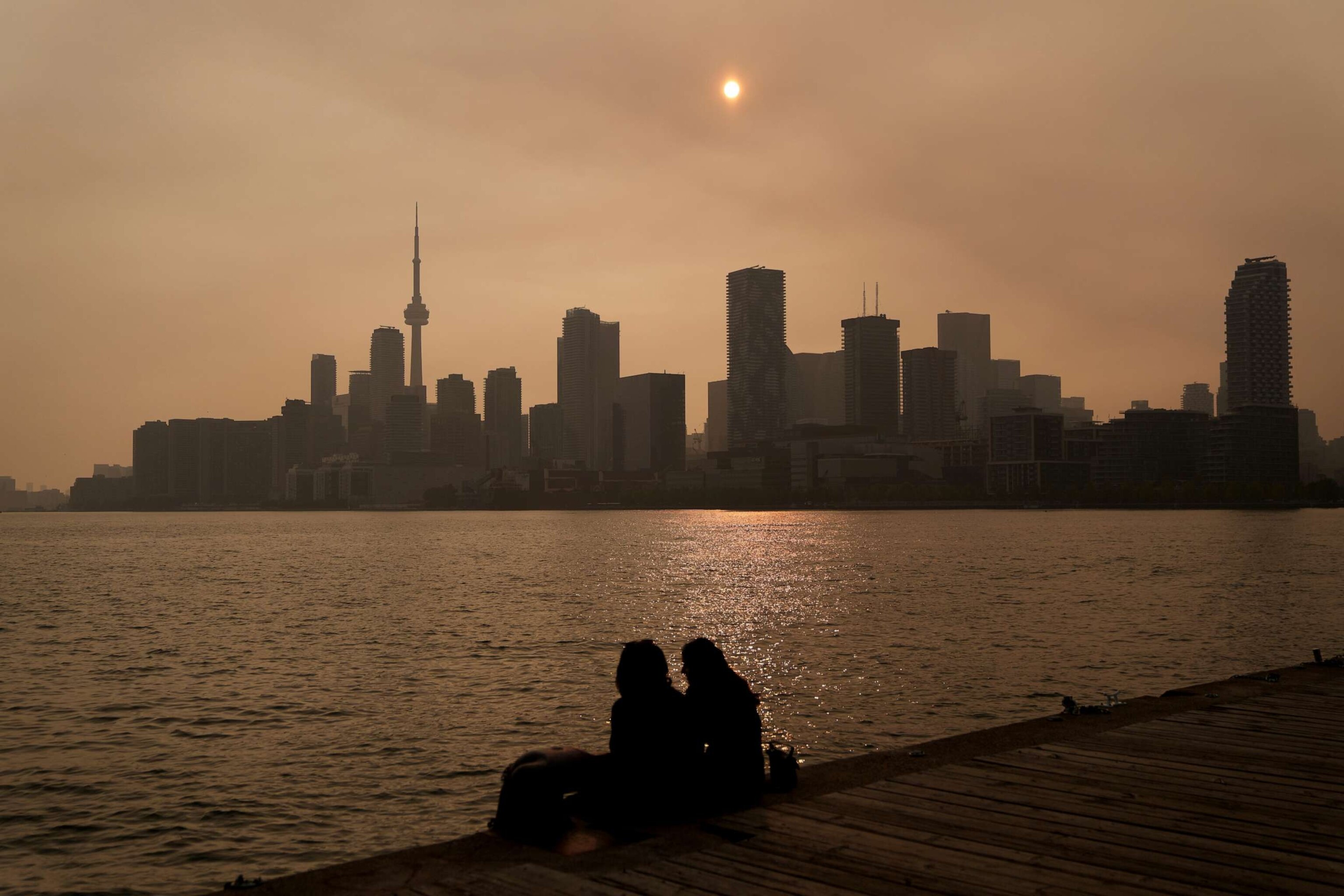 PHOTO: People watch the sunset as the smoke from wildfires is visible in Toronto on June 28, 2023.