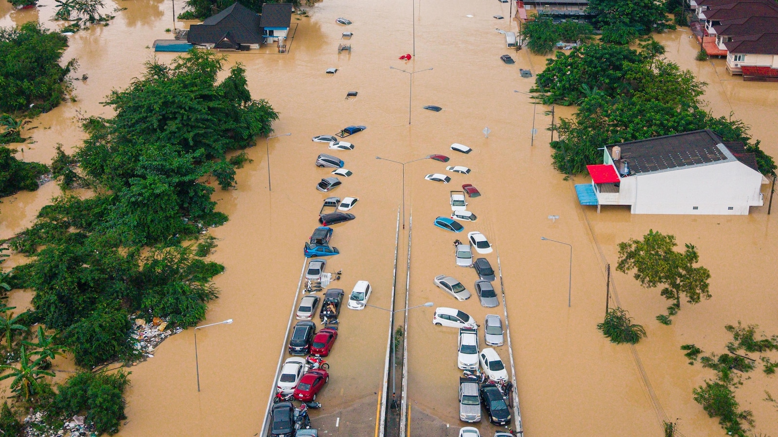 Families in Thailand perch on rooftops to escape flooding that has killed at least 33