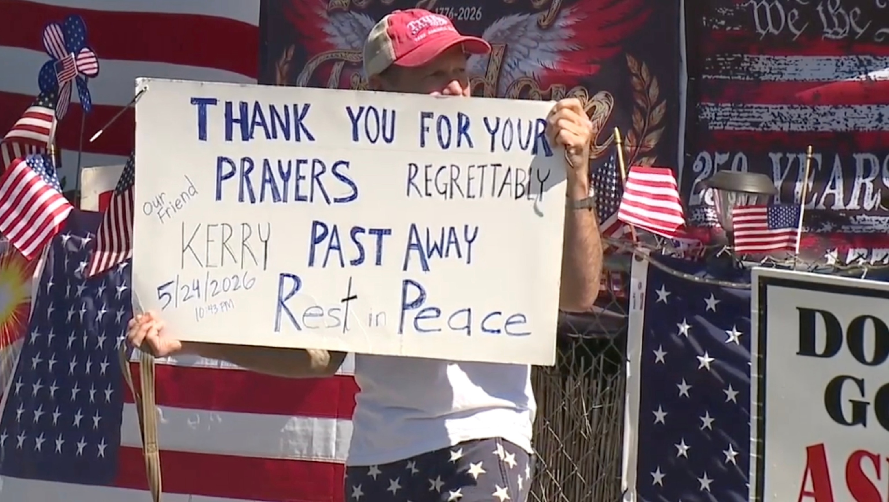 PHOTO: A man holds a sign outside the Escondido, Calif., home of Kerry George Sheron, who police said died days after he was allegedly attacked and beaten, May 20, 2026, outside his residence, which features a MAGA-themed display.