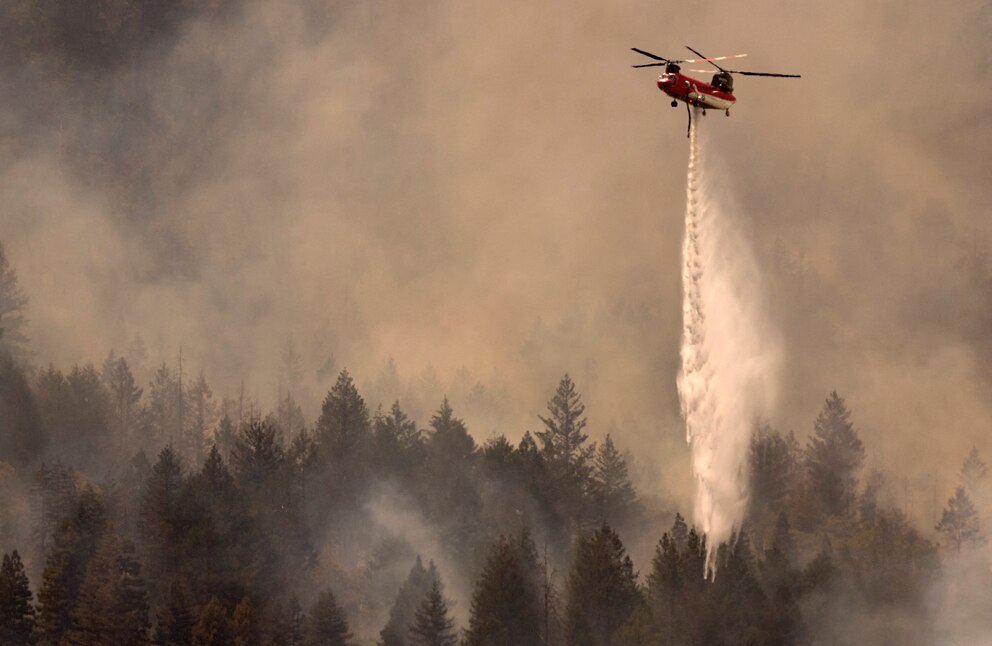 PHOTO: A helicopter drops water on the Pickett Fire