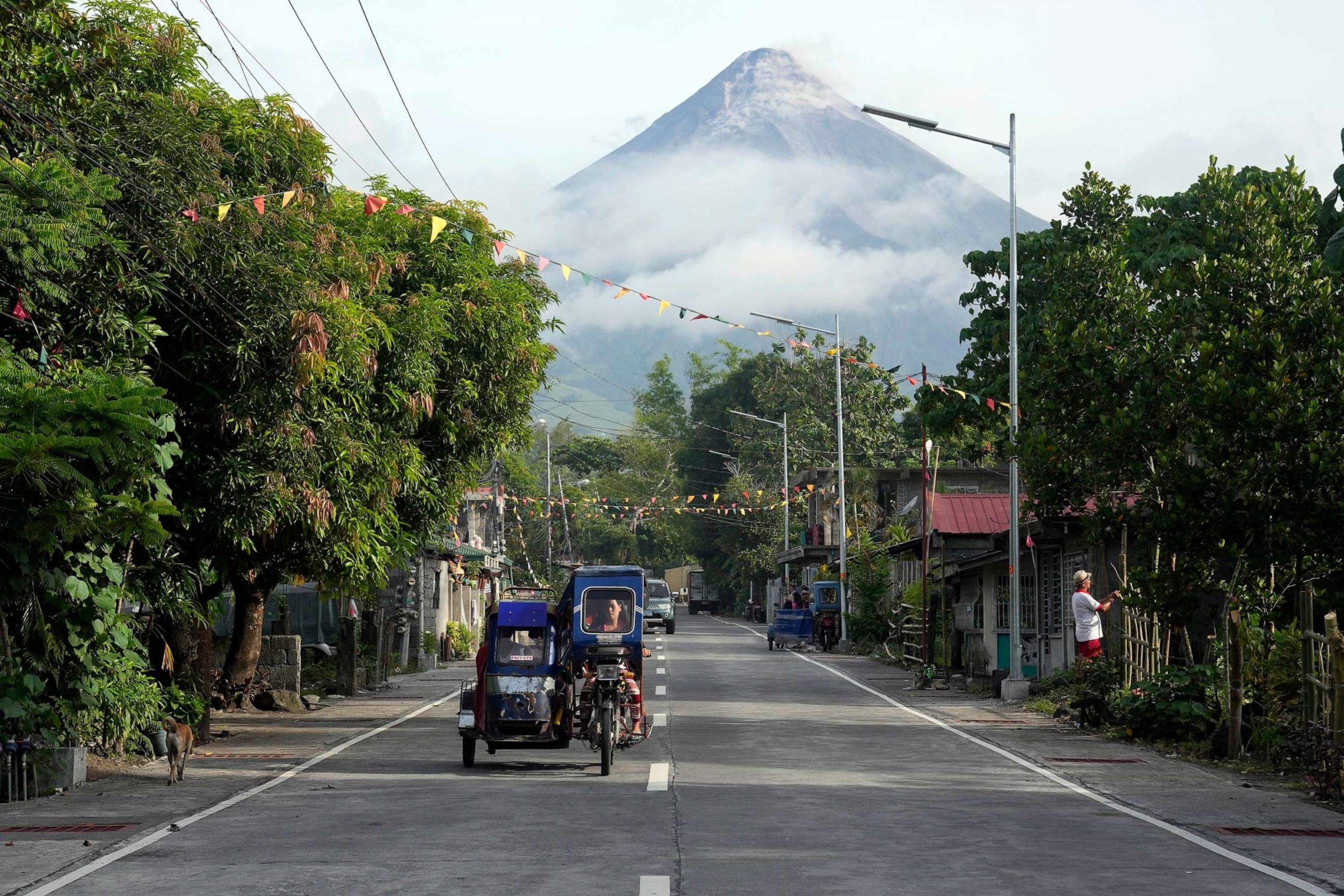 PHOTO: A woman drives a tricycle as Mayon volcano is seen from Legazpi, Albay province, northeastern Philippines, June 13, 2023.