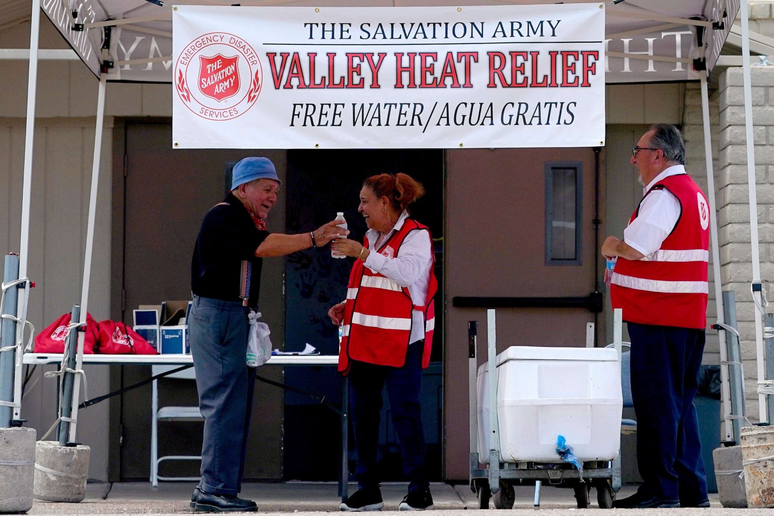 PHOTO: Salvation Army volunteer Francisca Corral, center, gives water to a man at a their Valley Heat Relief Station, July 11, 2023 in Phoenix.