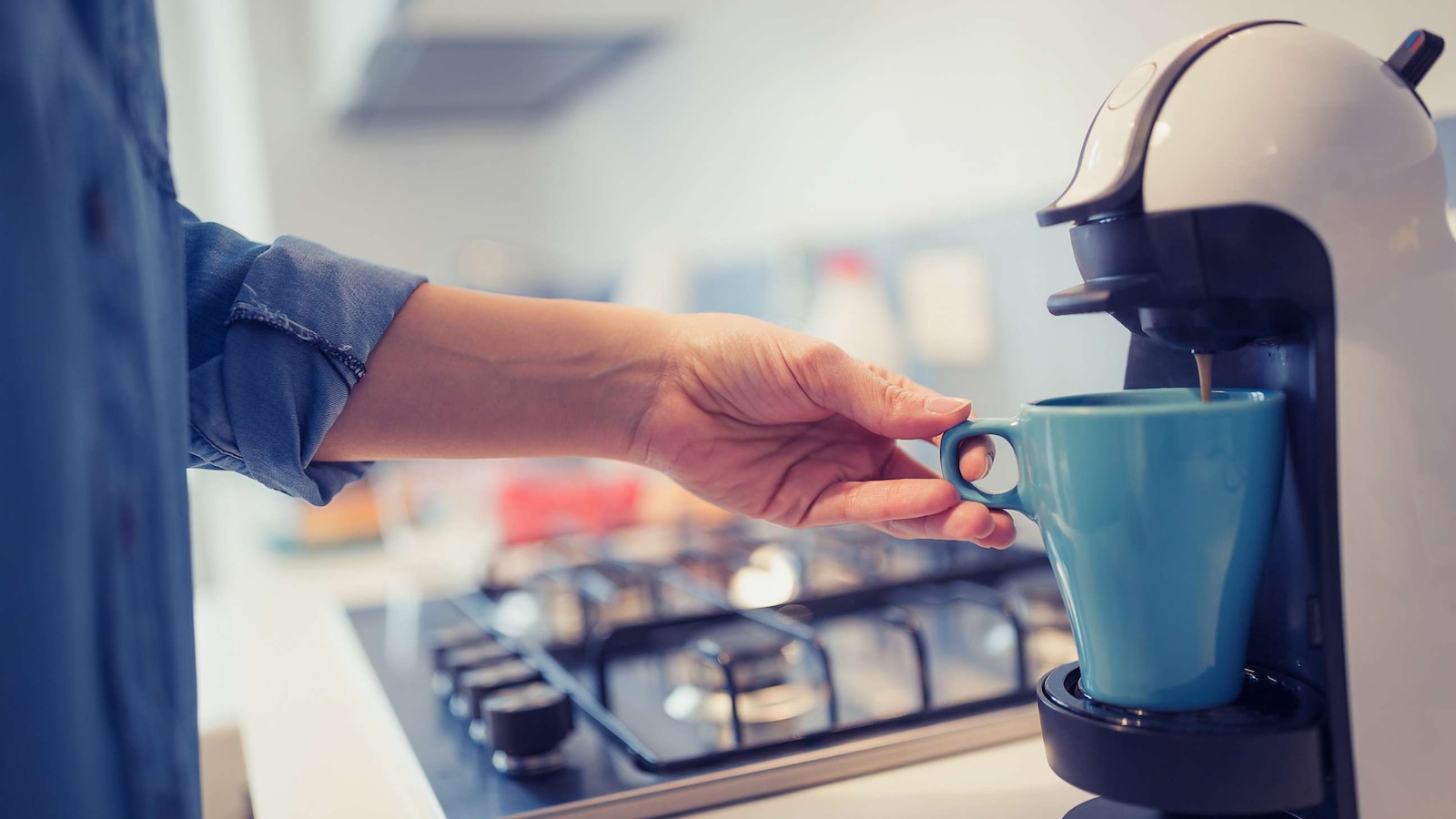 A woman makes coffee at home in the kitchen.