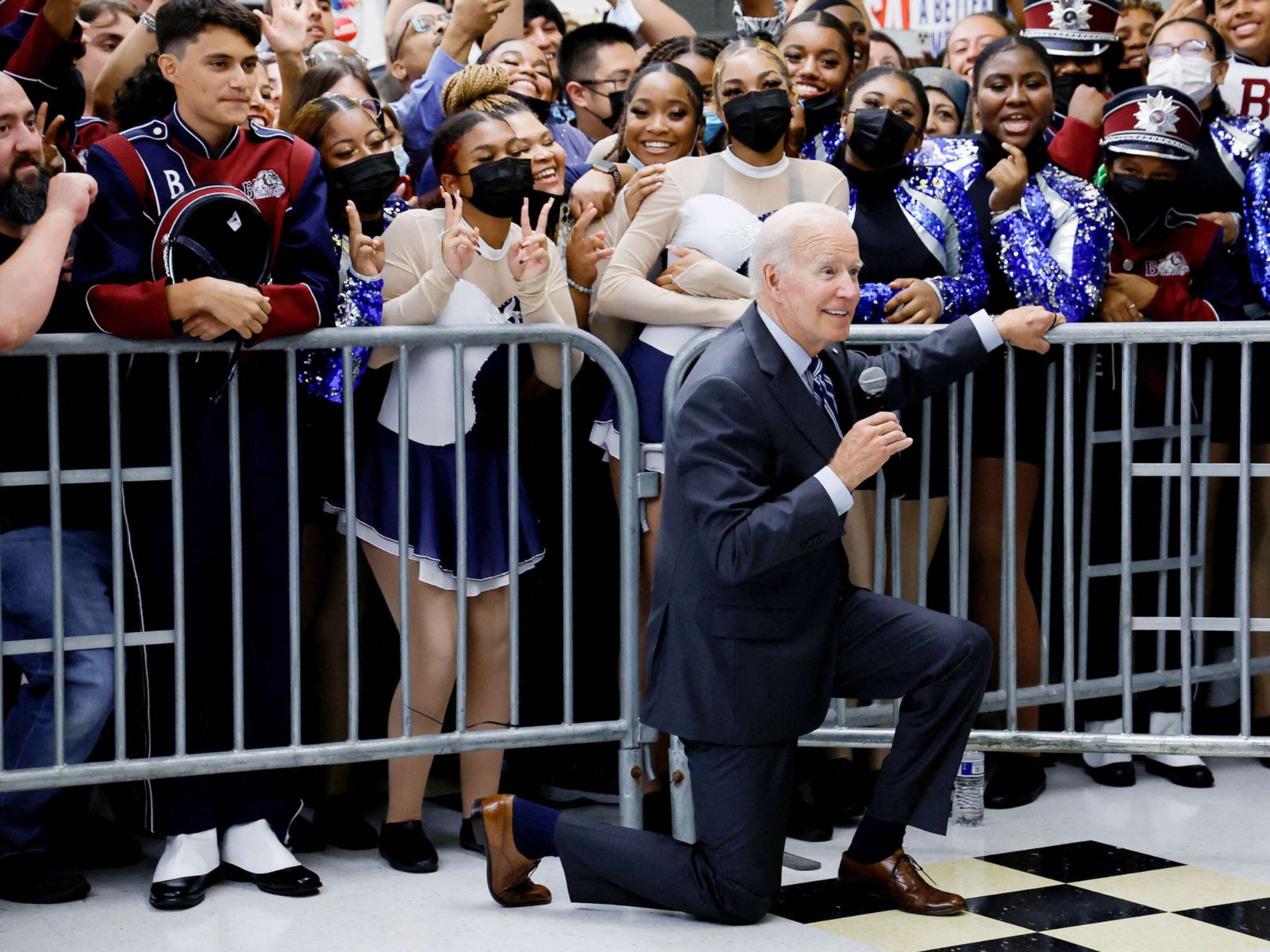 PHOTO: President Joe Biden kneels to pose for a picture as he participates in a Democratic National Committee rally at Richard Montgomery High School in Rockville, Md., Aug. 25, 2022.