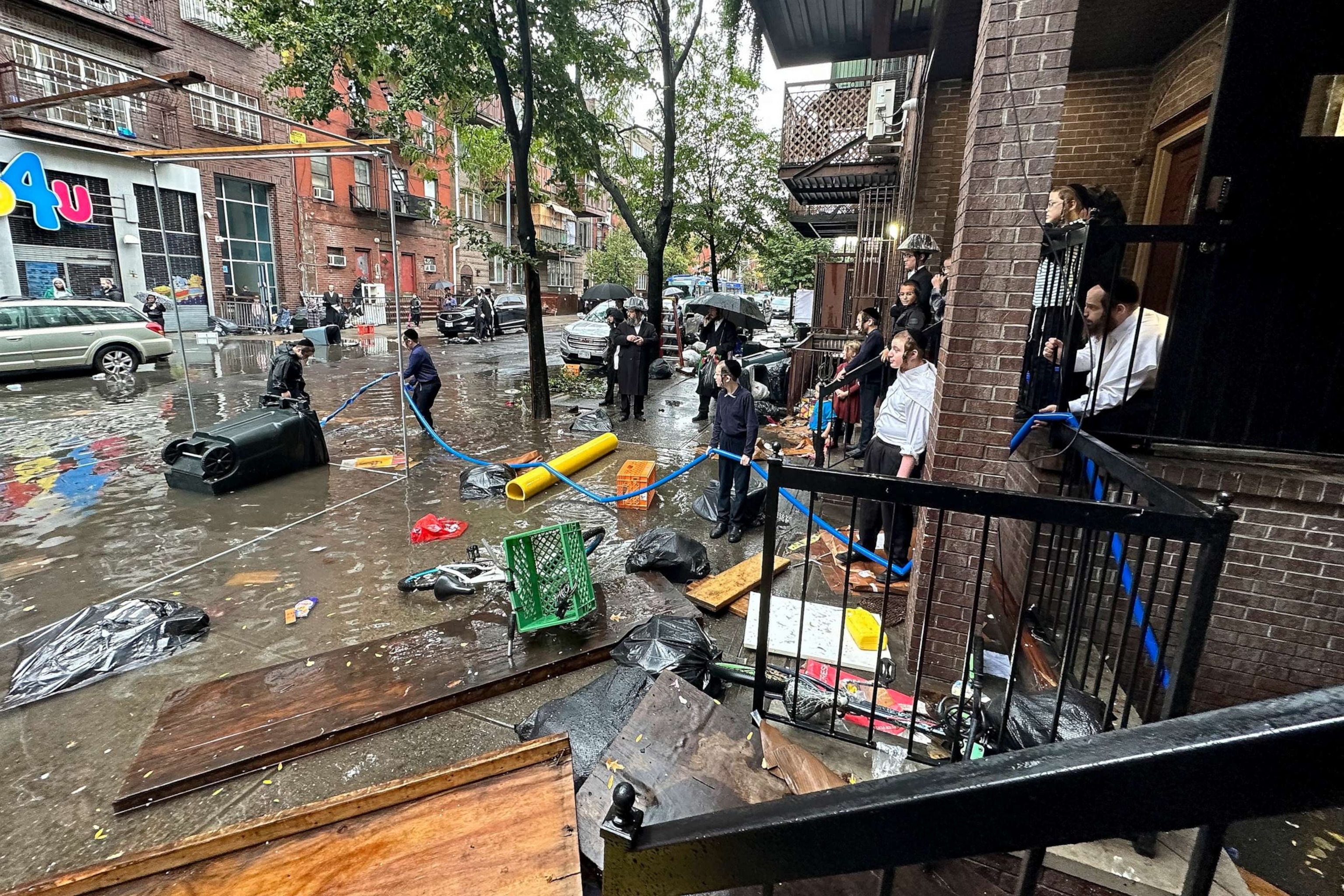 PHOTO: Residents watch as workers attempt to clear a drain in flood waters, Sept. 29, 2023, in the Brooklyn borough of New York.