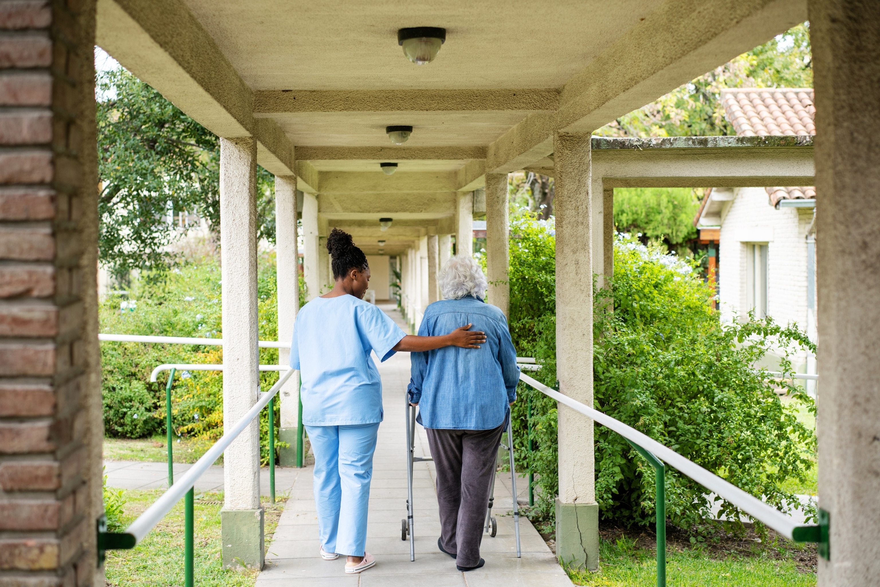 PHOTO: Nurse assisting senior woman with mobility walker outside nursing home