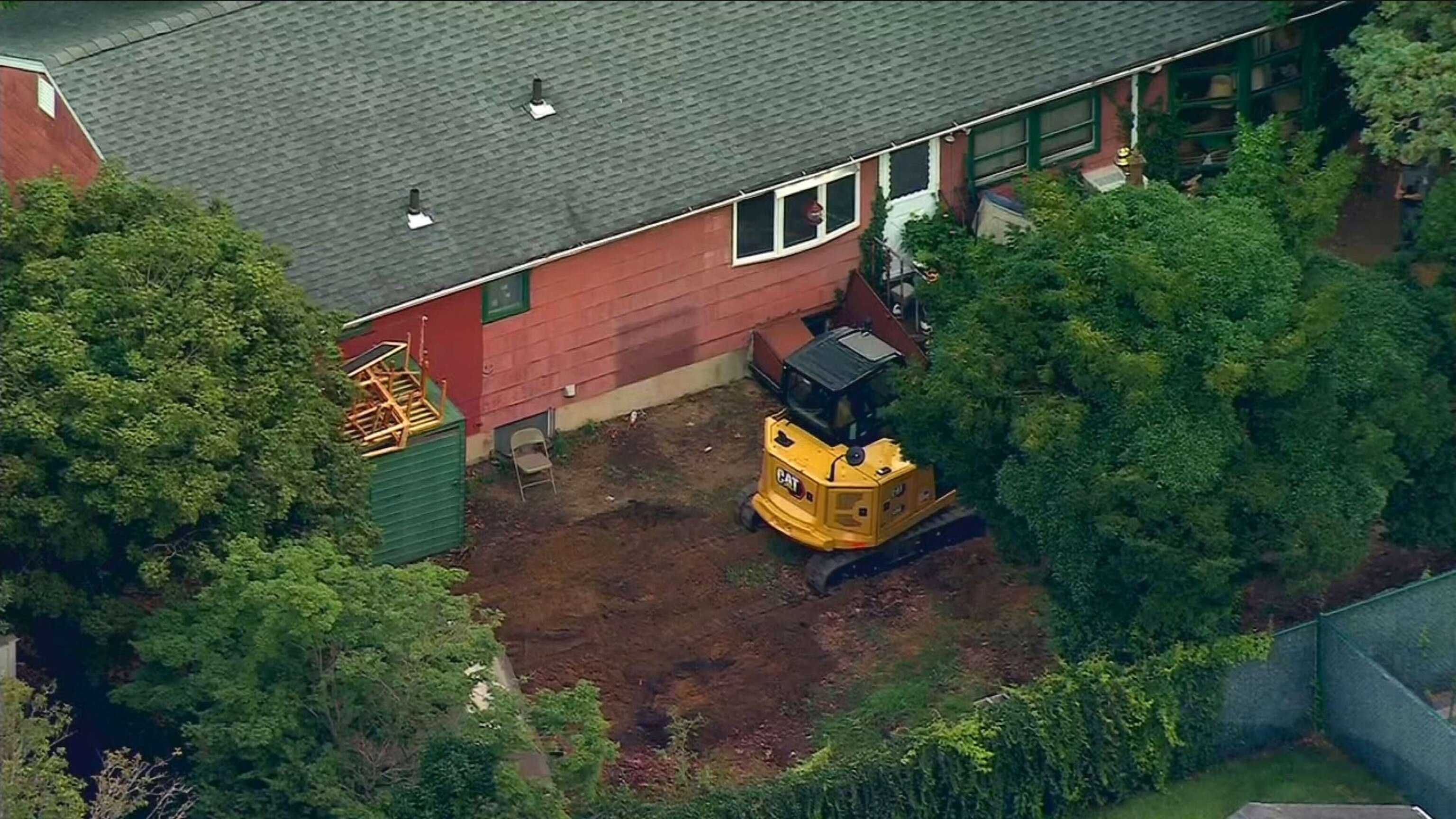 PHOTO: Heavy equipment sits in the backyard as investigators comb through the home of Rex Heuermann in Massapequa Park, N.Y. after he was arrested as a suspect in the Gilgo Beach killings, July 24, 2023.