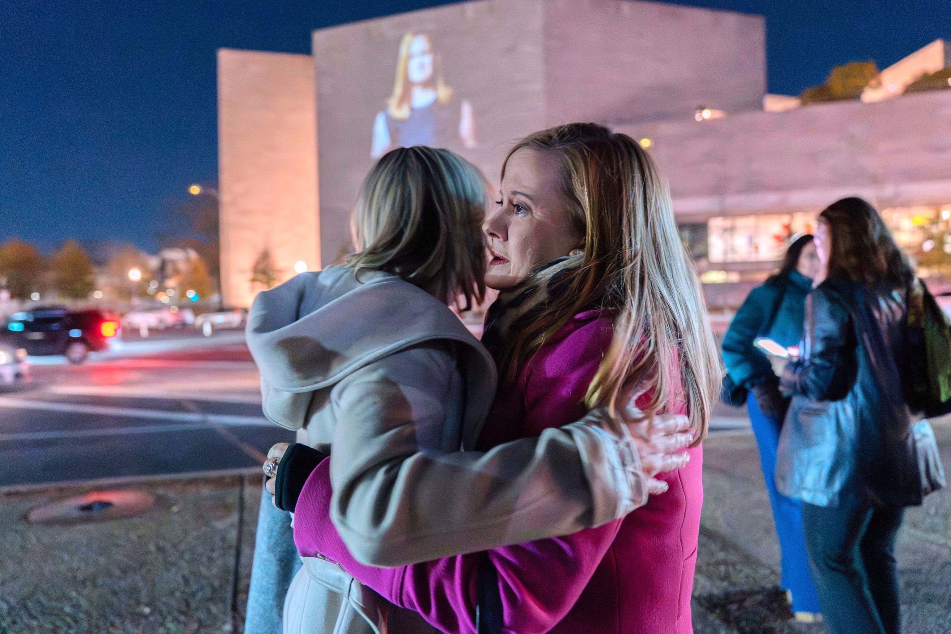 PHOTO: Liz Stein, right, gives a hug to Danielle Bensky as a World Without Exploitation projection is seen on the wall of the National Gallery in Washington, Monday, Nov. 17, 2025. 