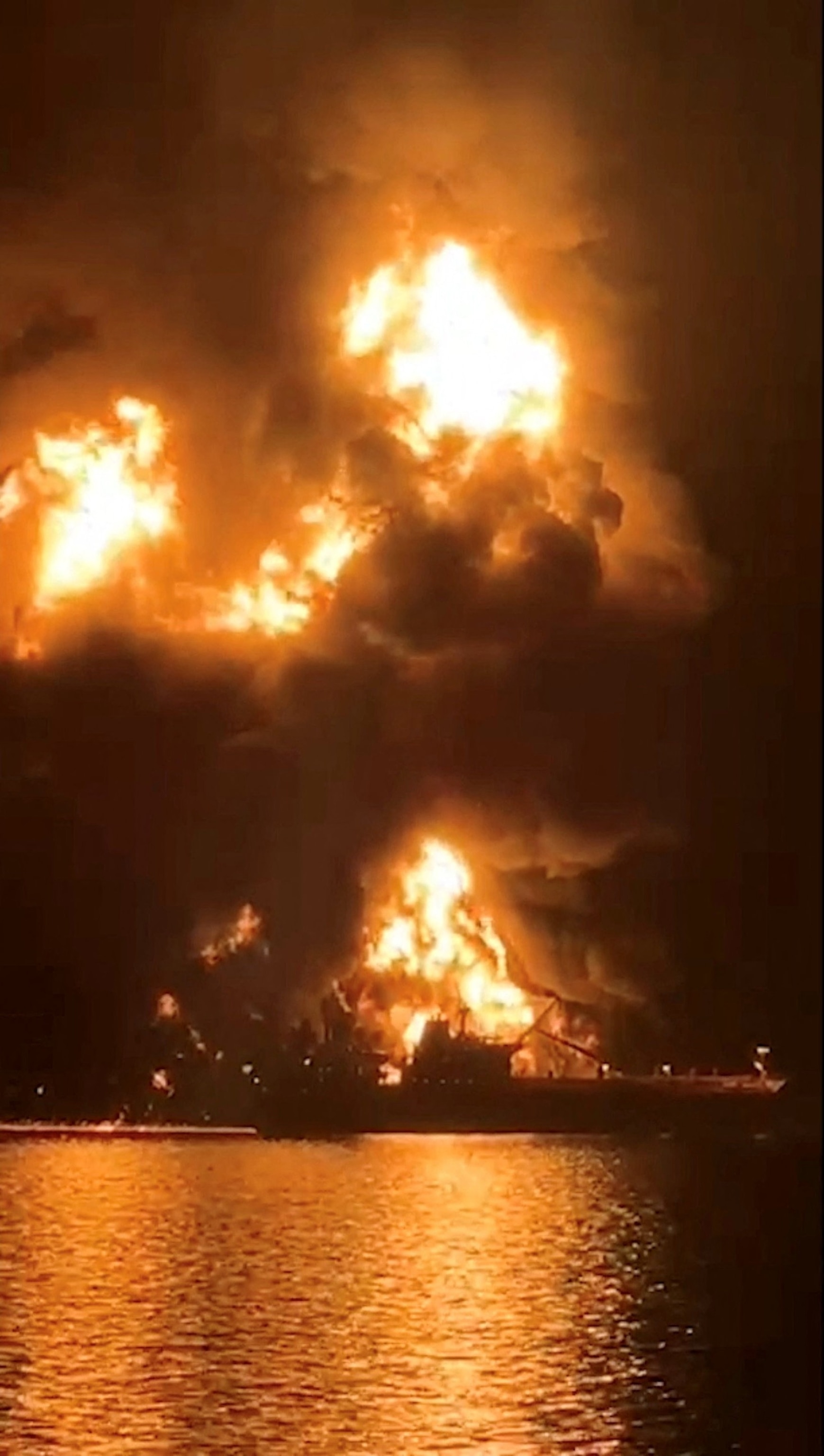PHOTO: A ship is illuminated by fire from a burning vessel, after Iranian explosive-laden boats appear to have attacked two fuel tankers in Iraqi waters setting them ablaze