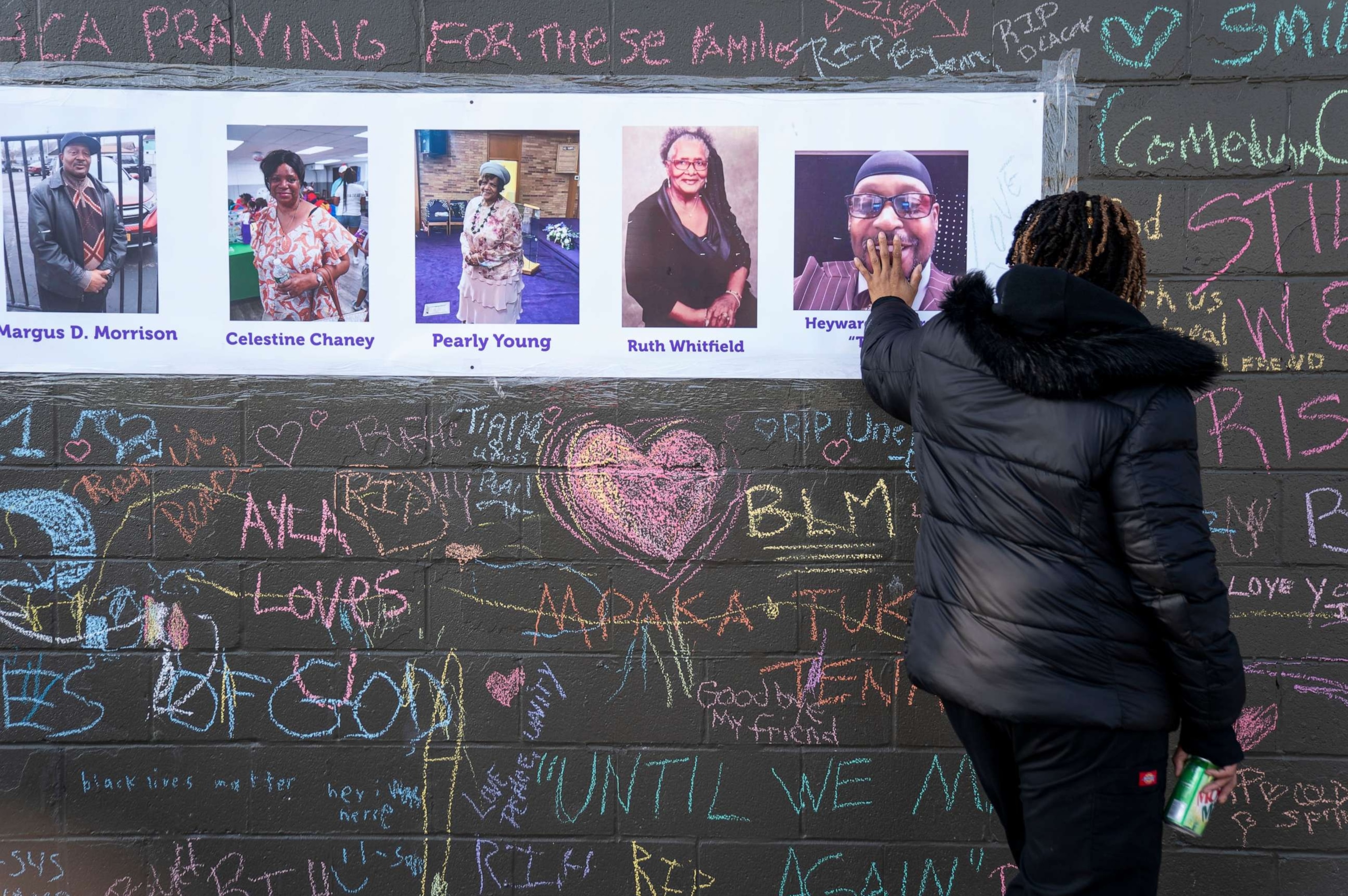 PHOTO: Kimberly Johnson, of Buffalo, places her hand on a photo of the late Hayward Patterson, at makeshift memorial across the street from the scene of a mass shooting at Tops Friendly Market, May 19, 2022 in Buffalo, New York.