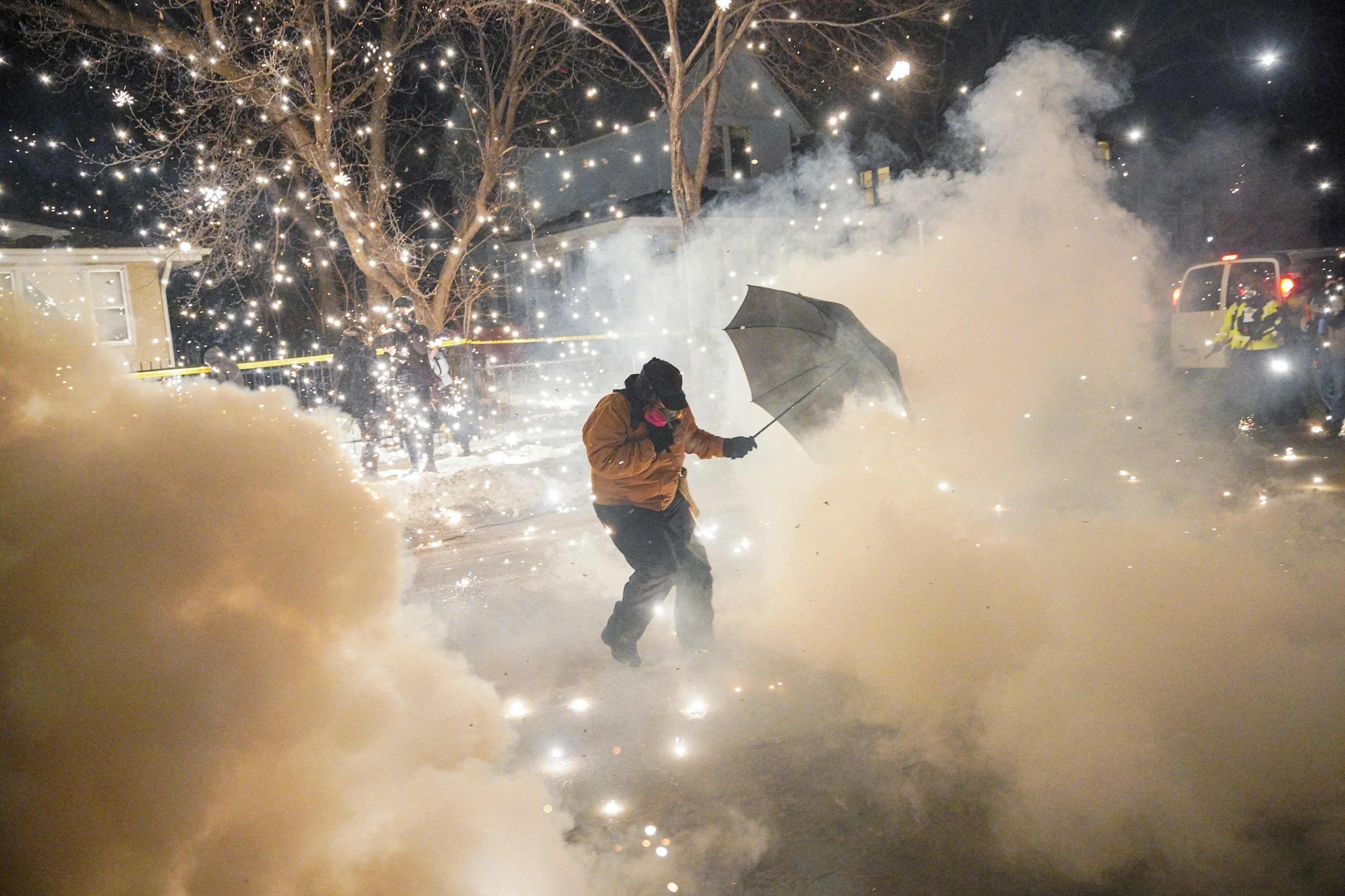PHOTO: A protesting community member attempts to protect themselves as federal agents fire munitions and pepper balls in north Minneapolis, Minnesota, U.S., Jan. 14, 2026.