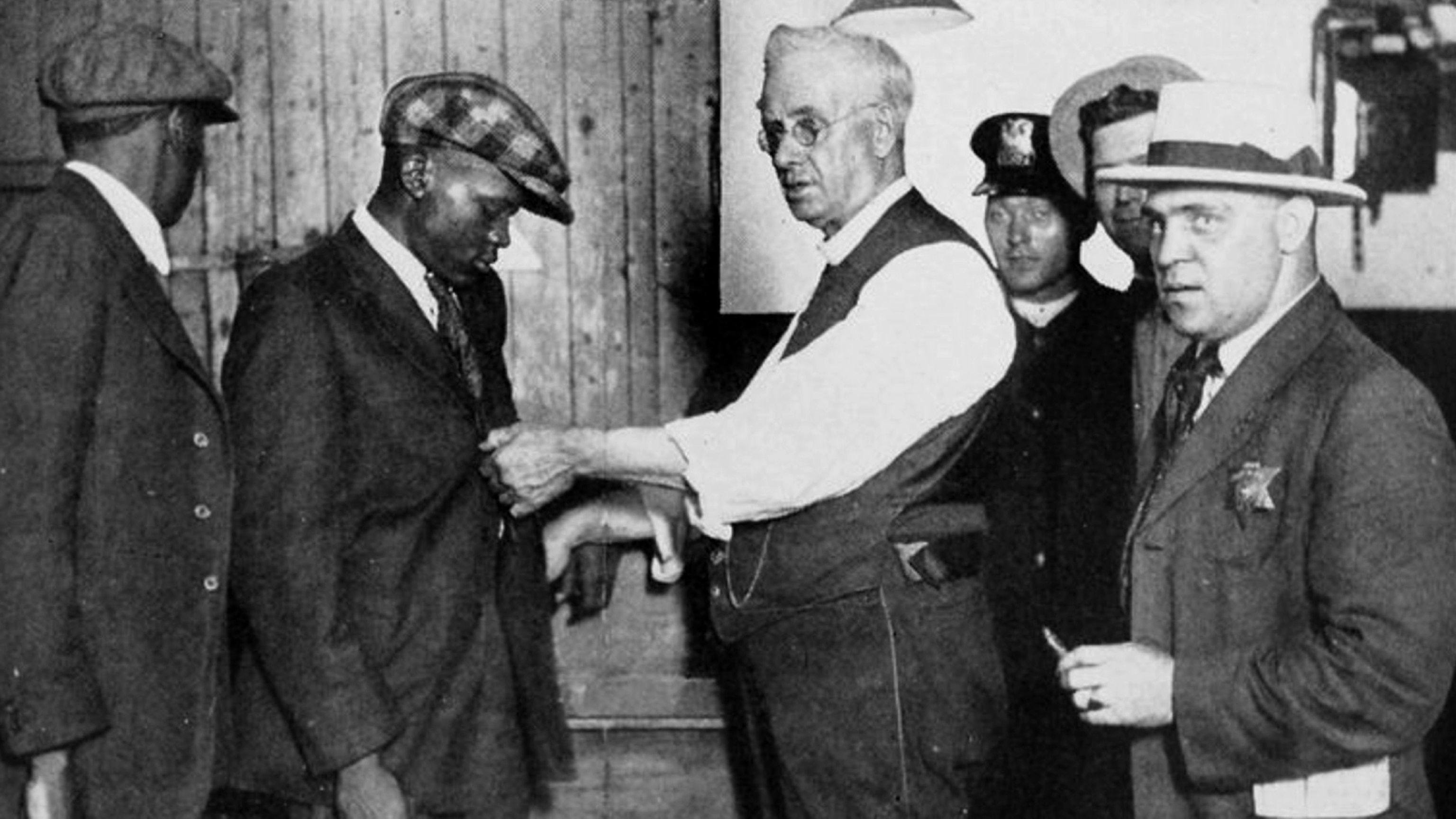 PHOTO: Officers search a Black man for arms at a police station in Chicago, Illinois, in 1922.