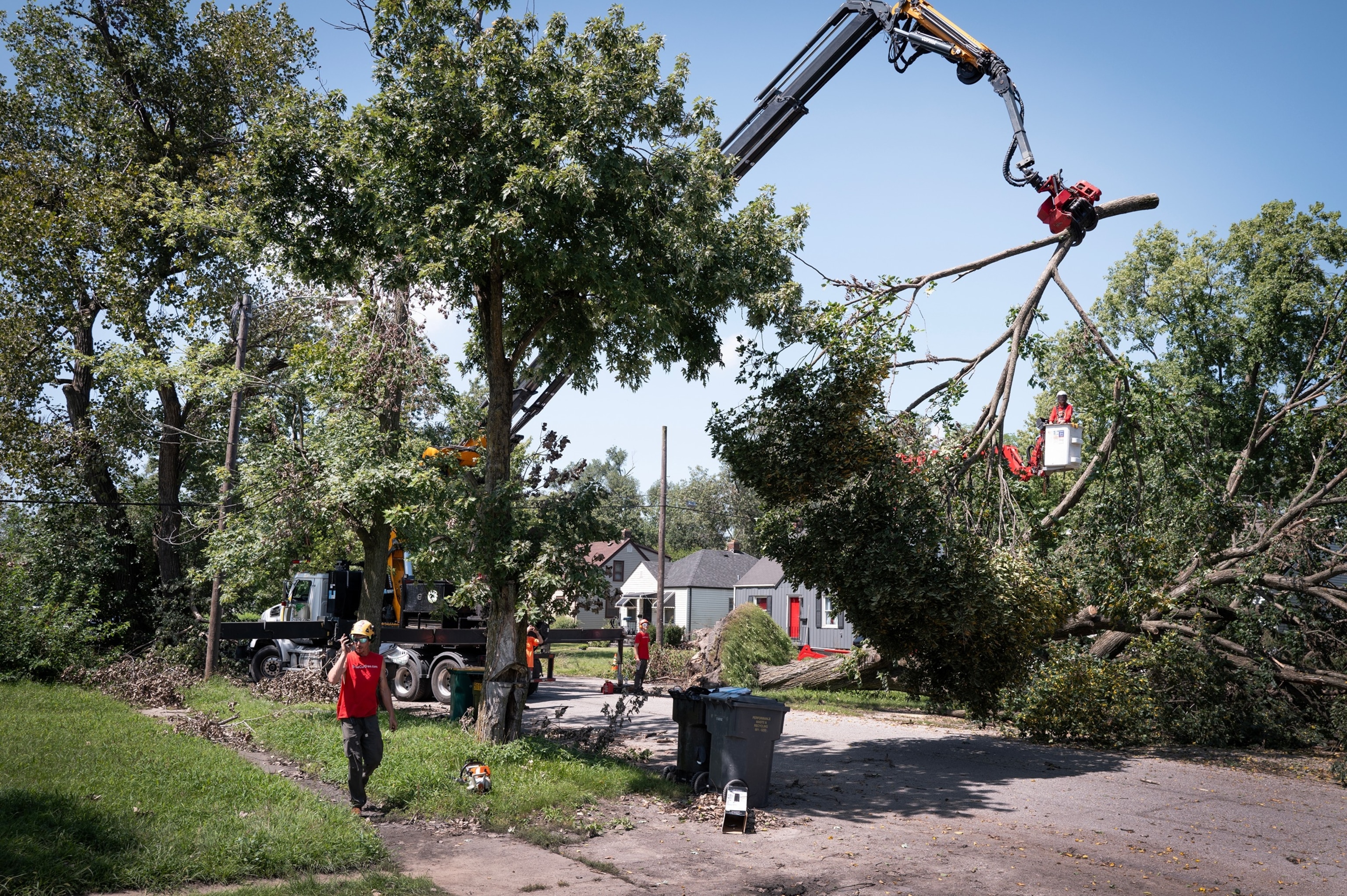 PHOTO: Workers remove a tree from the front of a home after it was toppled during a recent storm on Aug. 20, 2026, in Gary, Indiana.