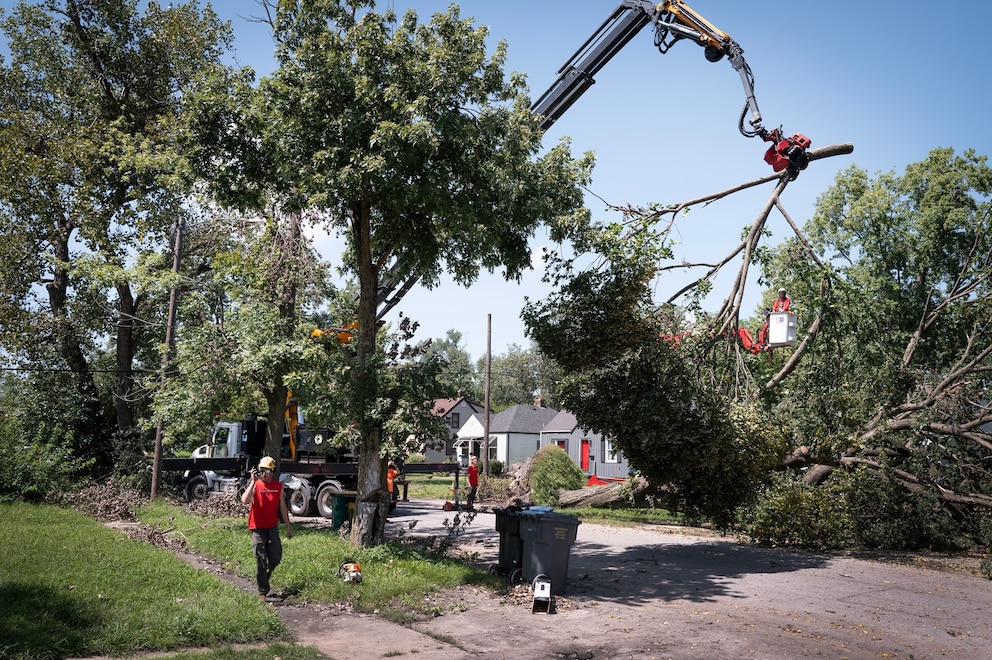 PHOTO: Workers remove a tree from the front of a home after it was toppled during a recent storm on Aug. 20, 2026, in Gary, Indiana.
