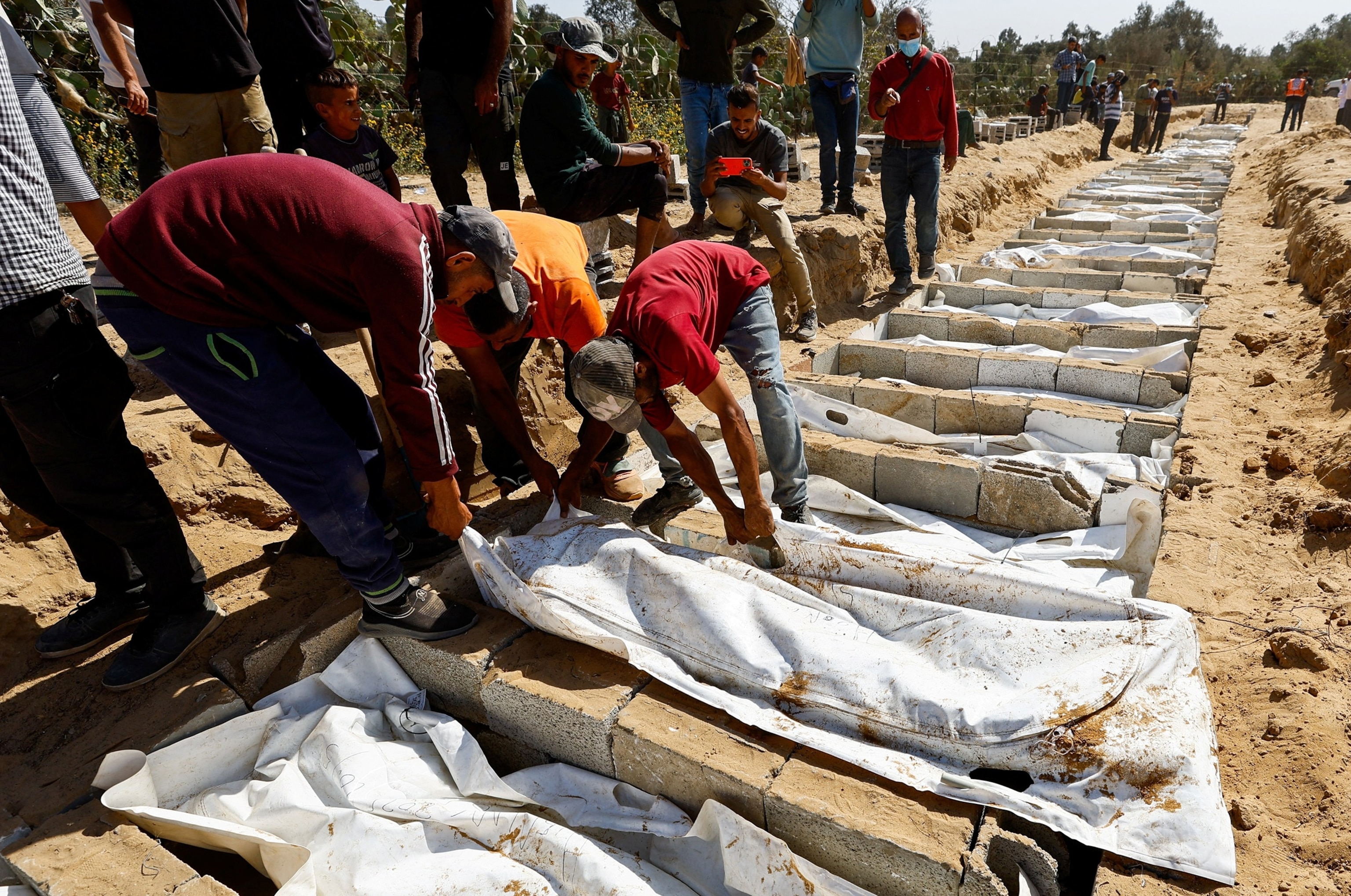 PHOTO: People bury at a mass burial site unidentified bodies of Palestinians who had been held in Israel during the war, after they were handed over by Israel, amid a ceasefire between Israel and Hamas in Gaza, in Deir Al-Balah, Oct. 22, 2025.