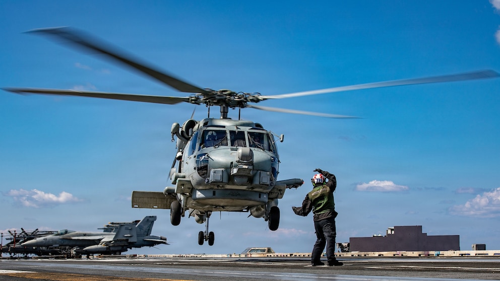 PHOTO: A U.S. sailor signals to an MH-60R Sea Hawk helicopter on the flight deck of the aircraft carrier, USS Gerald R. Ford while operating in support of Operation Epic Fury in the Eastern Mediterranean Sea, March 2, 2026. 