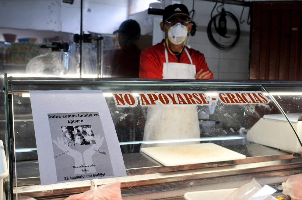 PHOTO: A man wearing a mask waits for clients at his shop, with a sign posted that reads in Spanish "We are all family in Epuyen, be supportive, use a mask" in Epuyen, Argentina, Jan. 11, 2019.