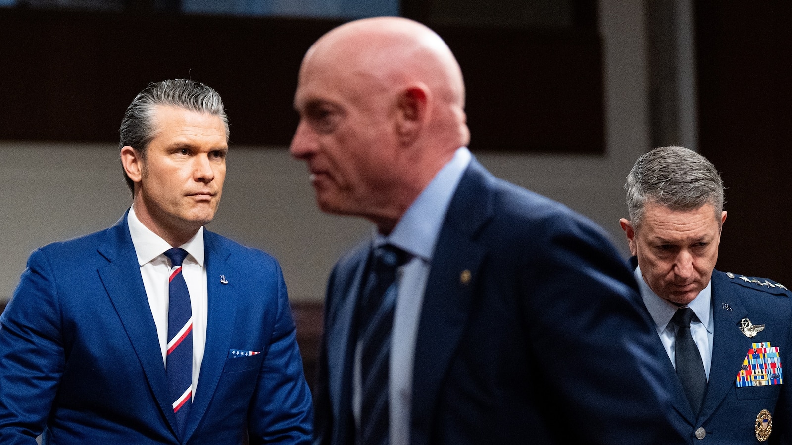 Sen. Mark Kelly walks past Secretary of Defense Pete Hegseth and Chairman of the Joint Chiefs of Staff Dan Caine before the start of a Senate Armed Services Committee hearing, April 30, 2026.
