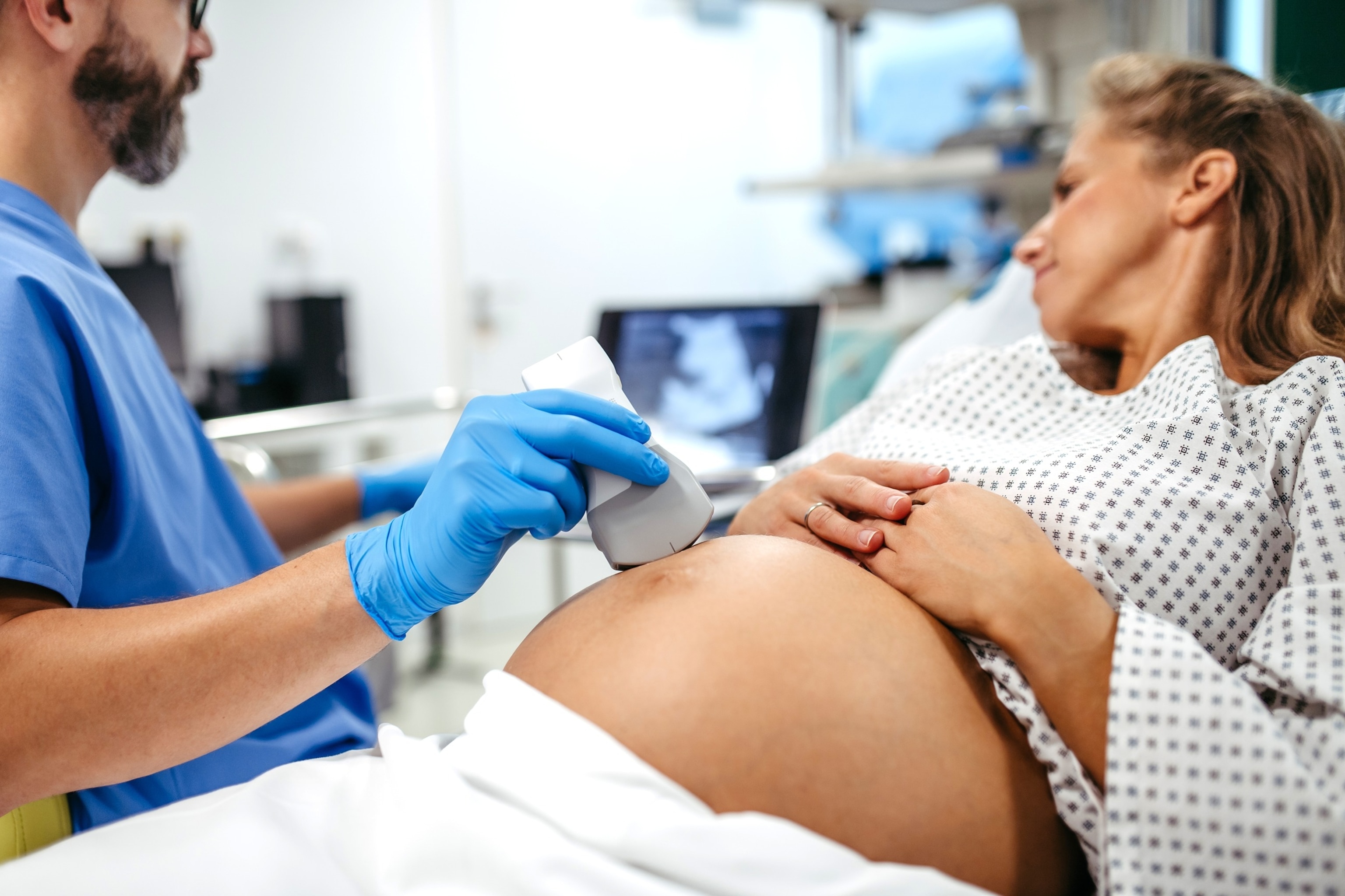 PHOTO: Ob/gyn doctor doing ultrasound of baby on pregnant woman. Woman having sonogram. Prenatal visit or care during third trimester of pregnancy. Pregnant woman on pregnancy check-up in doctor’s office.