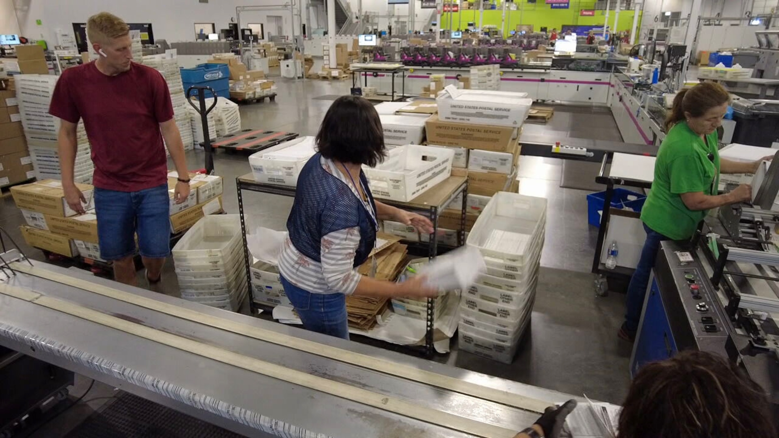 PHOTO: Inside Runbeck Election Services, workers stuff envelopes with ballots and prepare them to be mailed to voters.