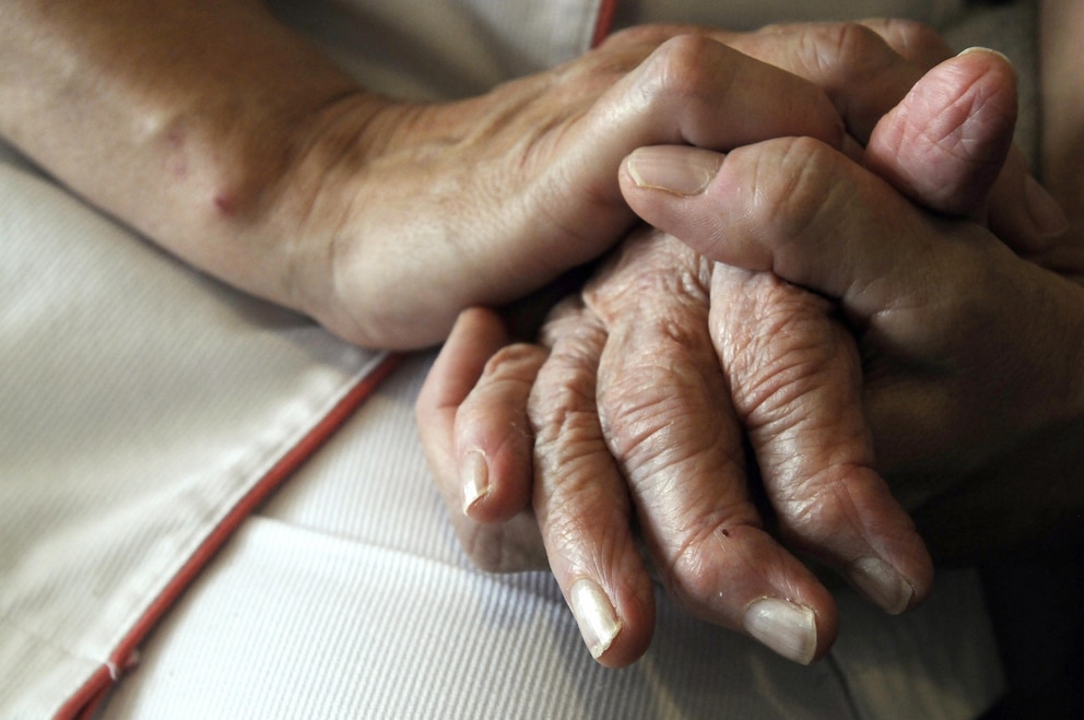 PHOTO: A nurse holds the hands of a person suff