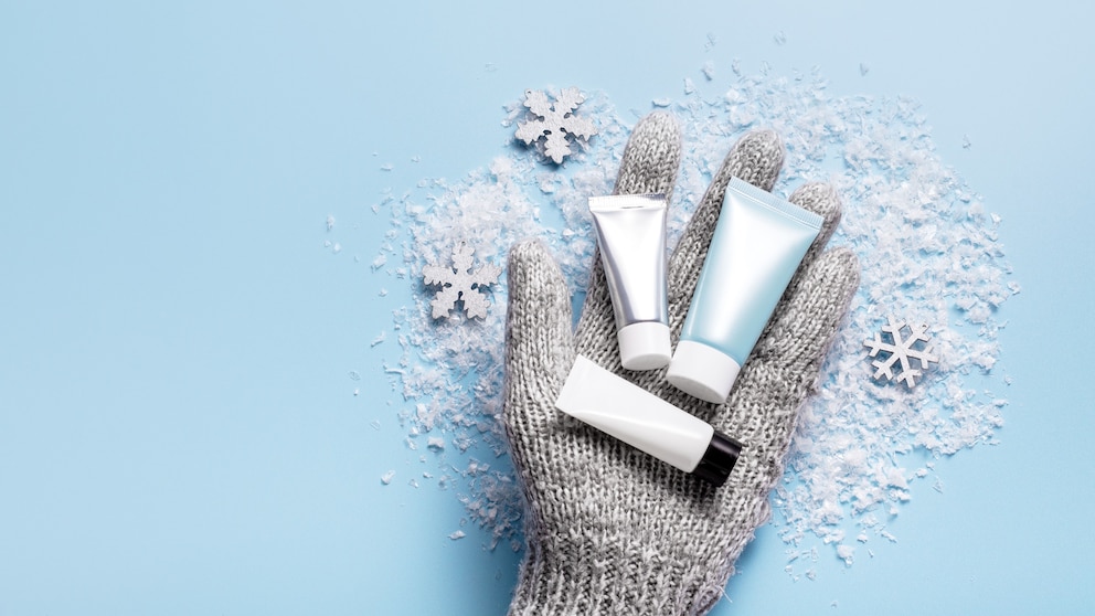 PHOTO: Winter skincare concept with a hand in grey mitten holding a winter cosmetic set.