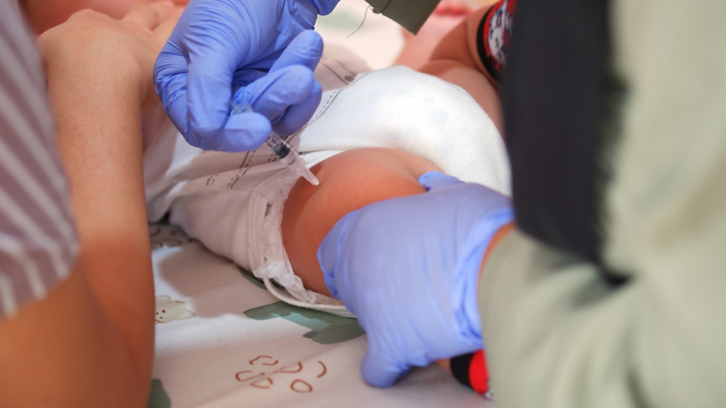 PHOTO: A doctor immunizes an infant on tight.