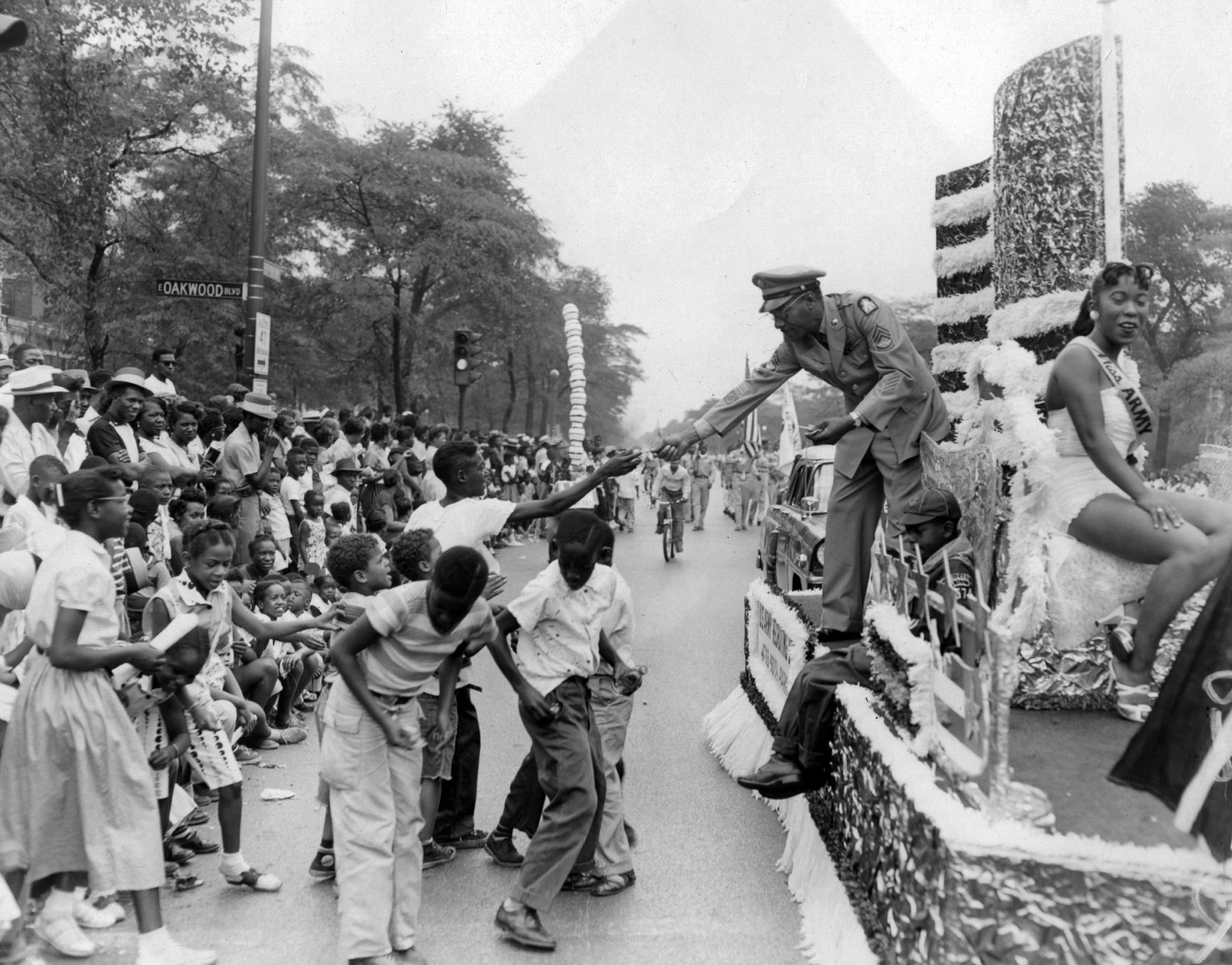 PHOTO: A uniformed officer hands treats and candies out to members of the crowd watching the annual Bud Billiken parade, sponsored by the Chicago Defender, in Chicago, in 1984. 