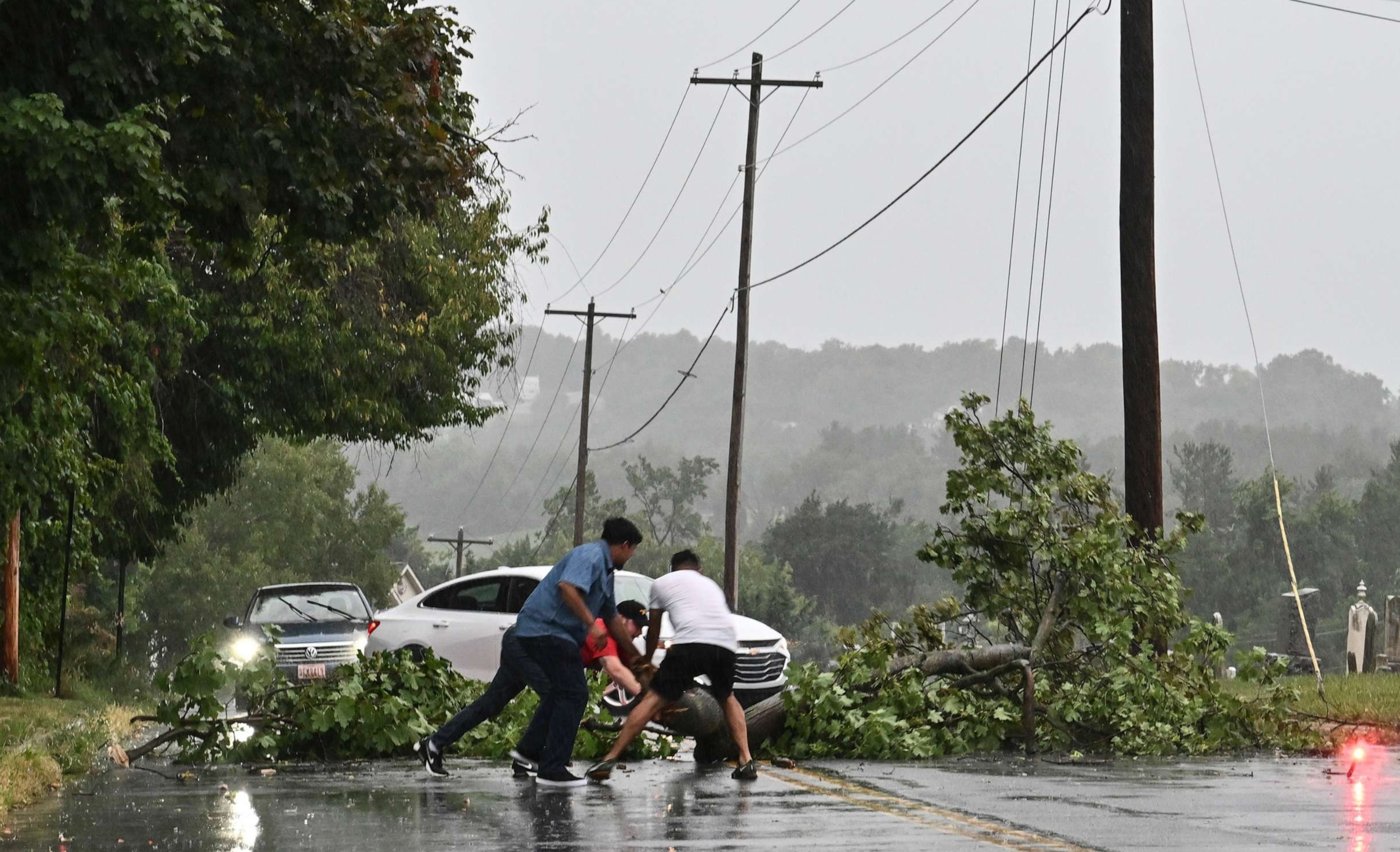 PHOTO: Motorists stop to remove a fallen tree from the roadway following a severe thunderstorm on August 7, 2023 in Myersville, Md.