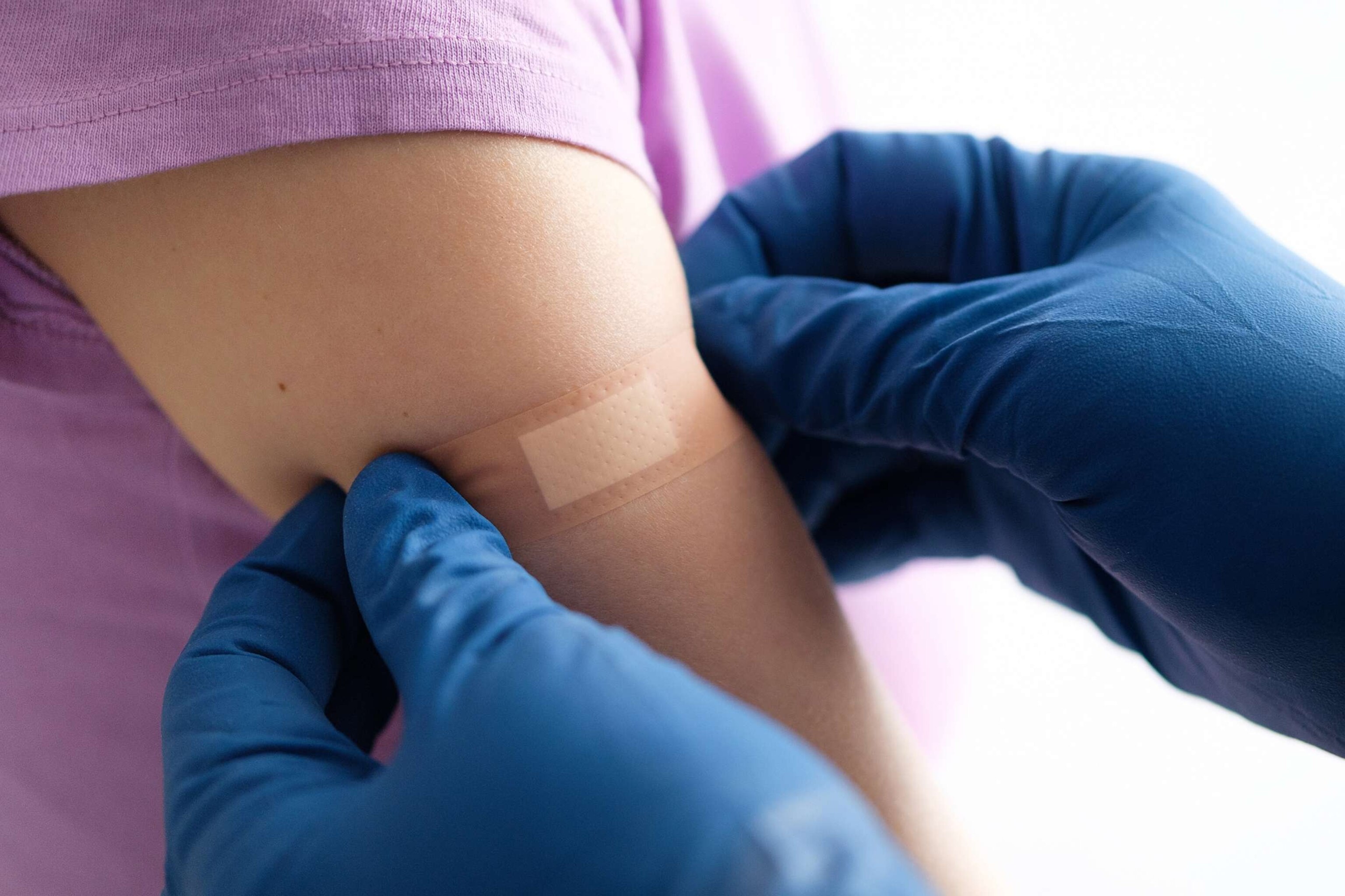 PHOTO: In this undated stock photo, a gloved doctor applies a bandage to a young patient after an injection.