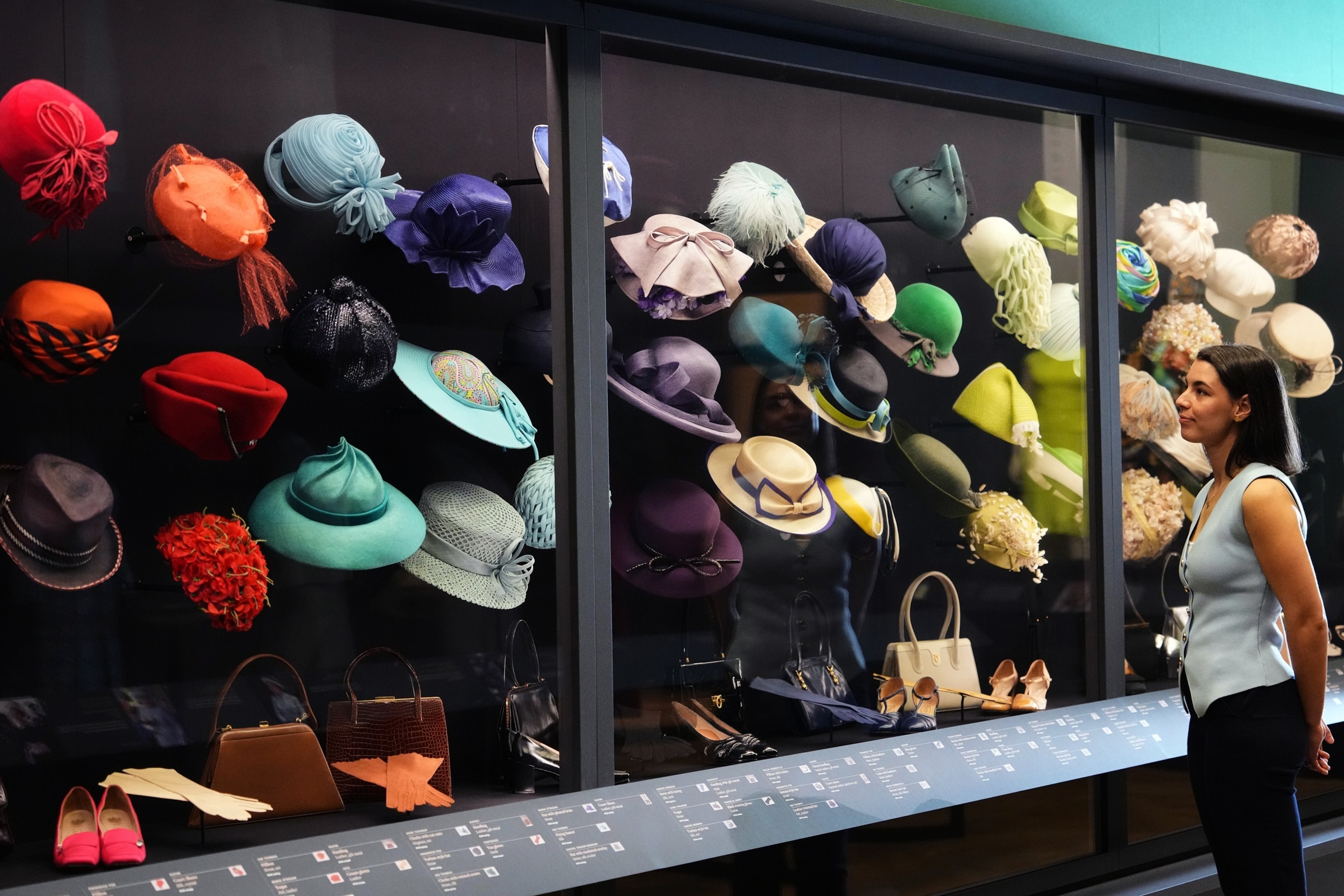 PHOTO: A member of the Royal Collection Trust staff looks towards hats, bags and shoes worn by Queen Elizabeth, on display at 'Queen Elizabeth II: Her Life in Style' exhibition, at The King's Gallery at Buckingham Palace in London, April 9, 2026.