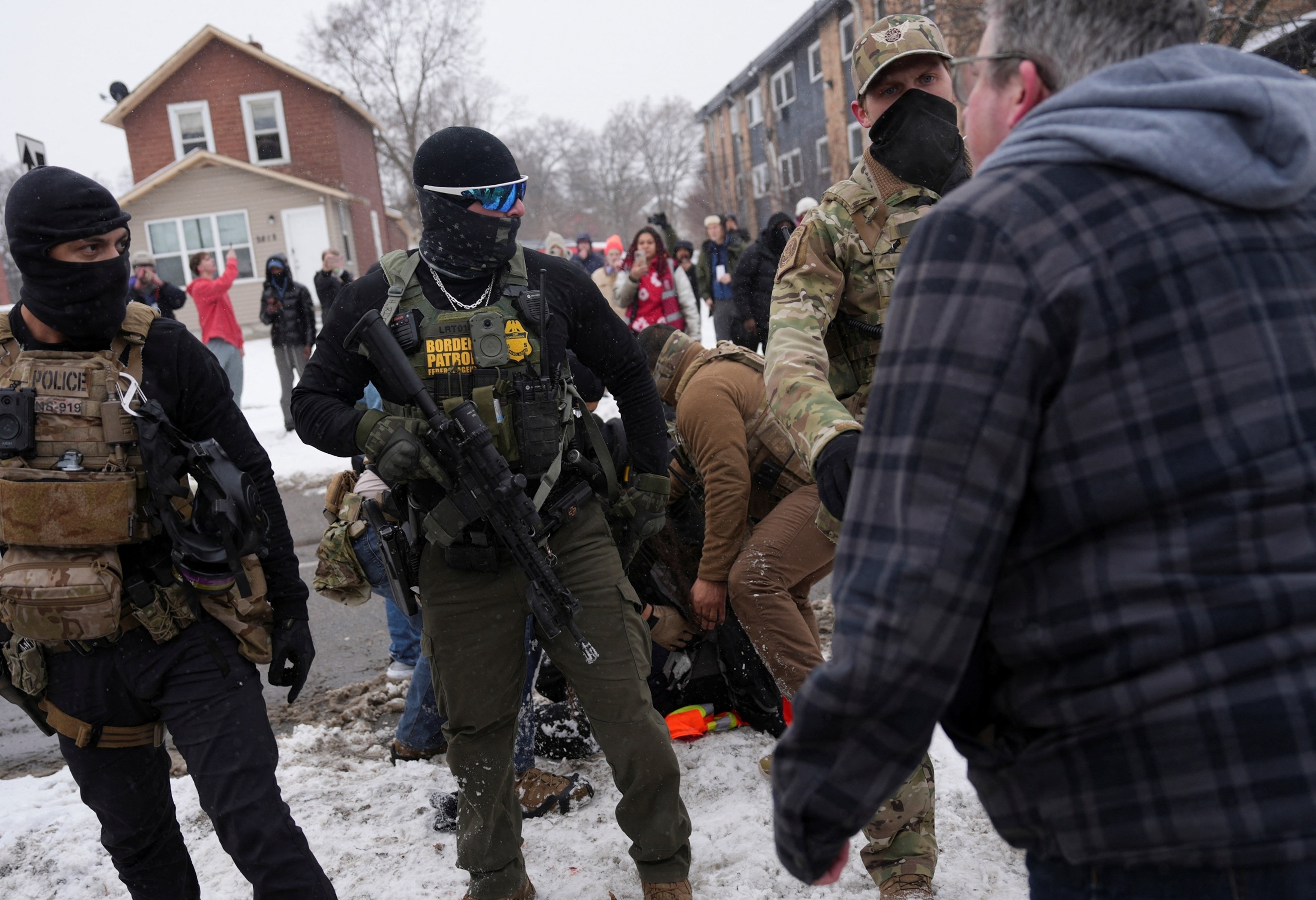 FOTO: Un hombre se enfrenta a agentes federales mientras una persona es detenida, mientras continúa la aplicación de medidas de inmigración en Minneapolis, el 21 de enero de 2026.