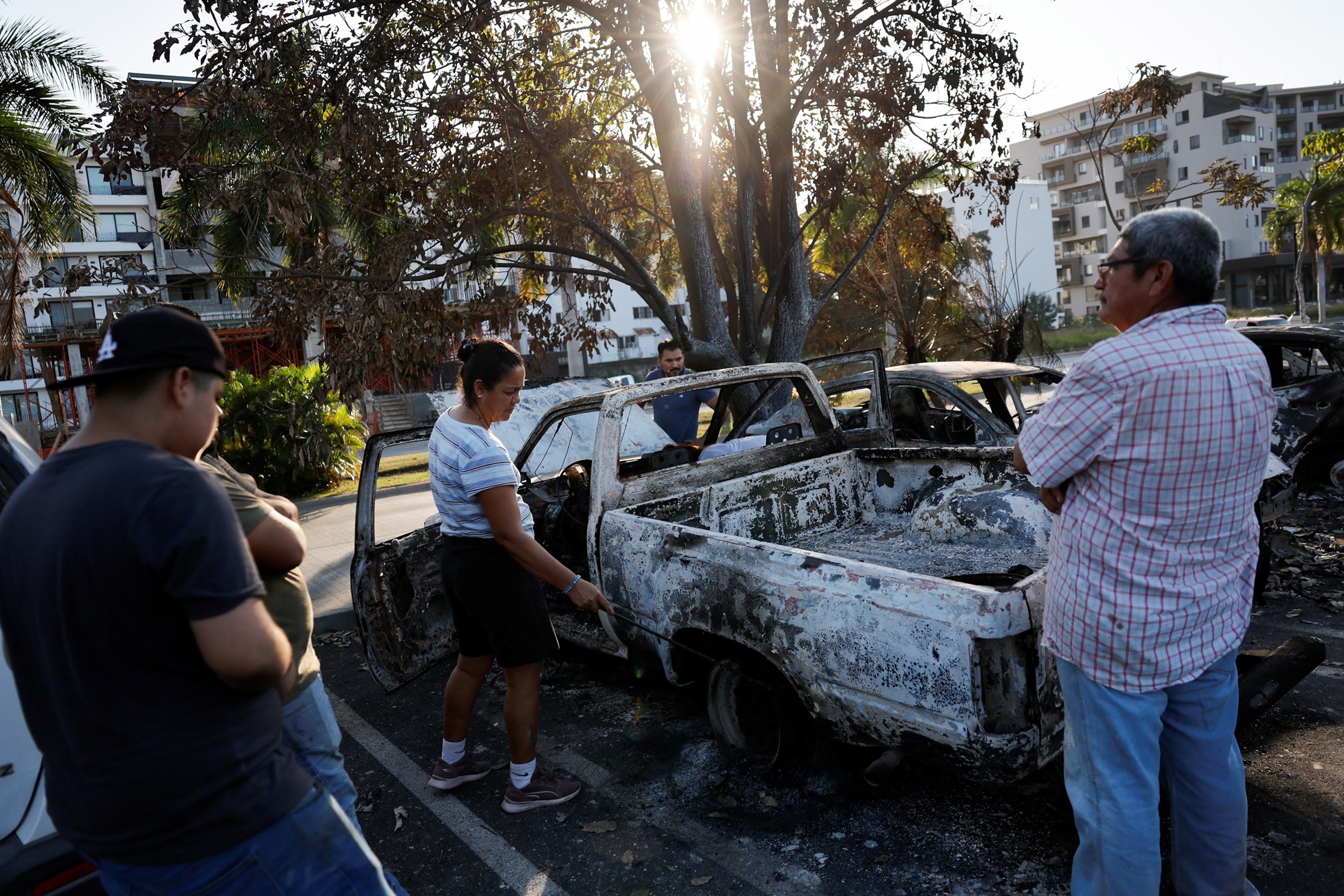 PHOTO: People inspect their vehicles, consumed by flames, in a supermarket parking lot days after a series of blockades and attacks in Puerto Vallarta, Mexico, Feb. 24, 2026. 