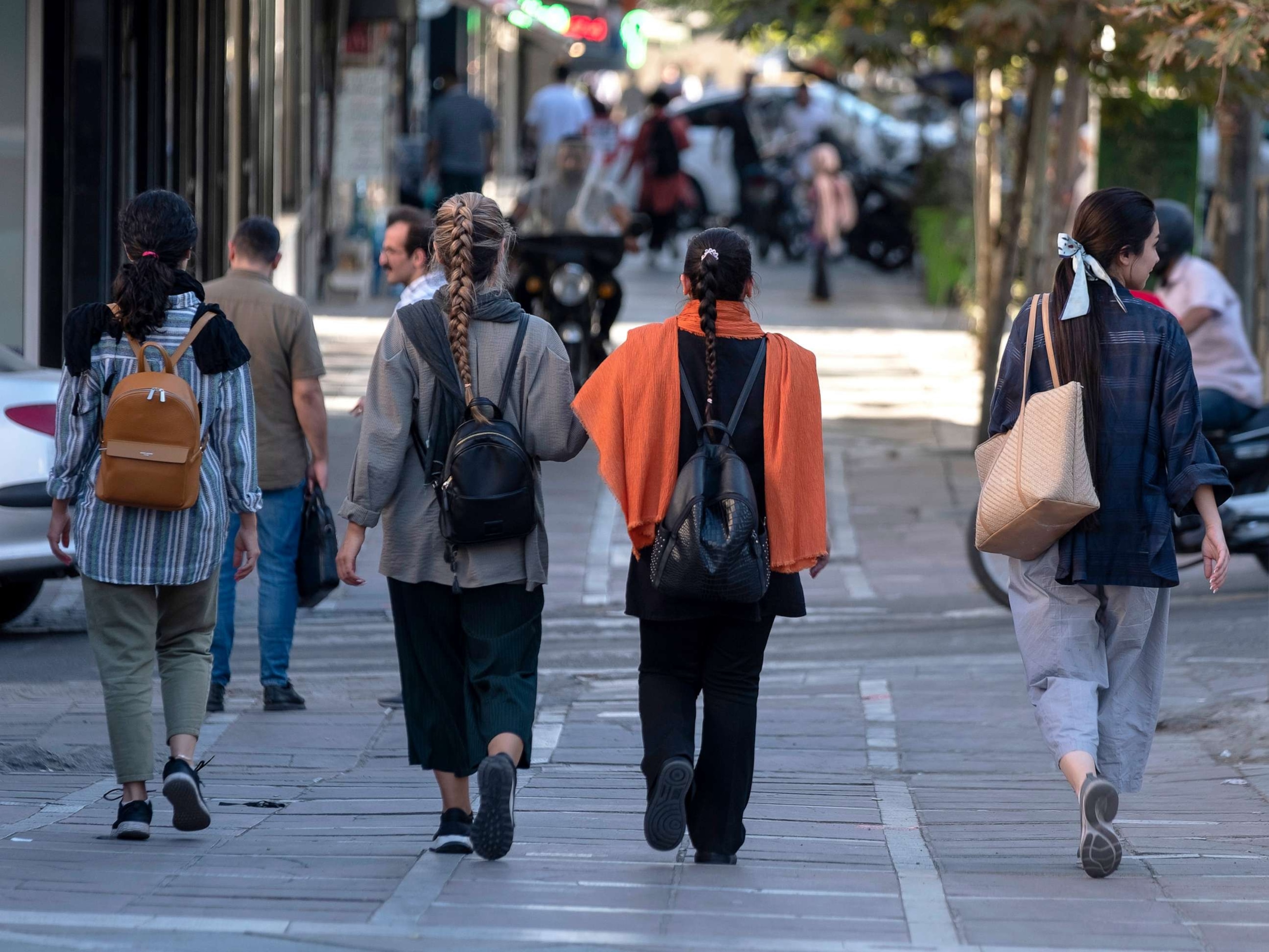 PHOTO: Iranian women without wearing mandatory headscarves, walk along an avenue in downtown Tehran, on Sept. 12, 2023.