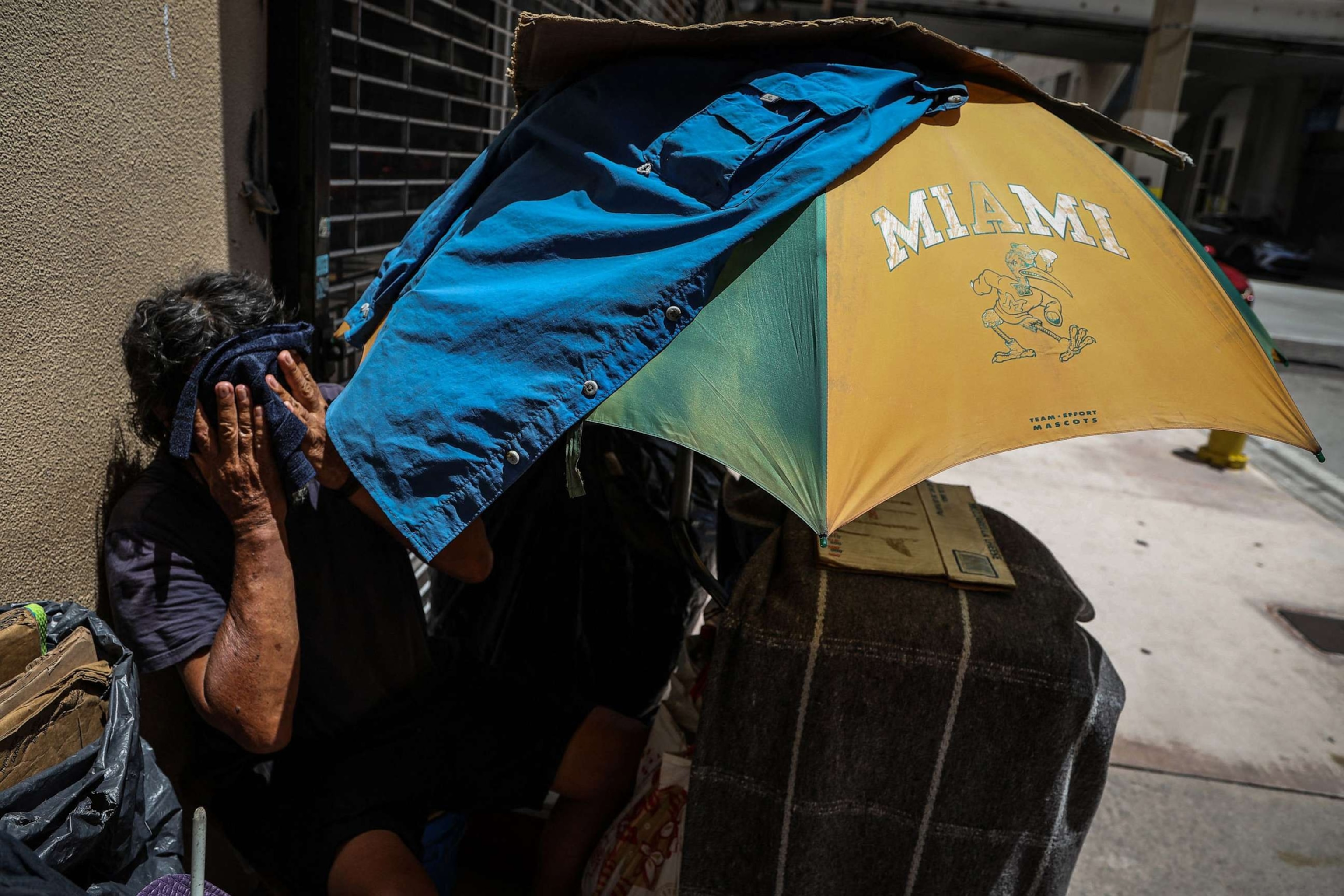 PHOTO: A homeless person wipes their face with a damp towel during a heatwave in Miami on June 26, 2023.