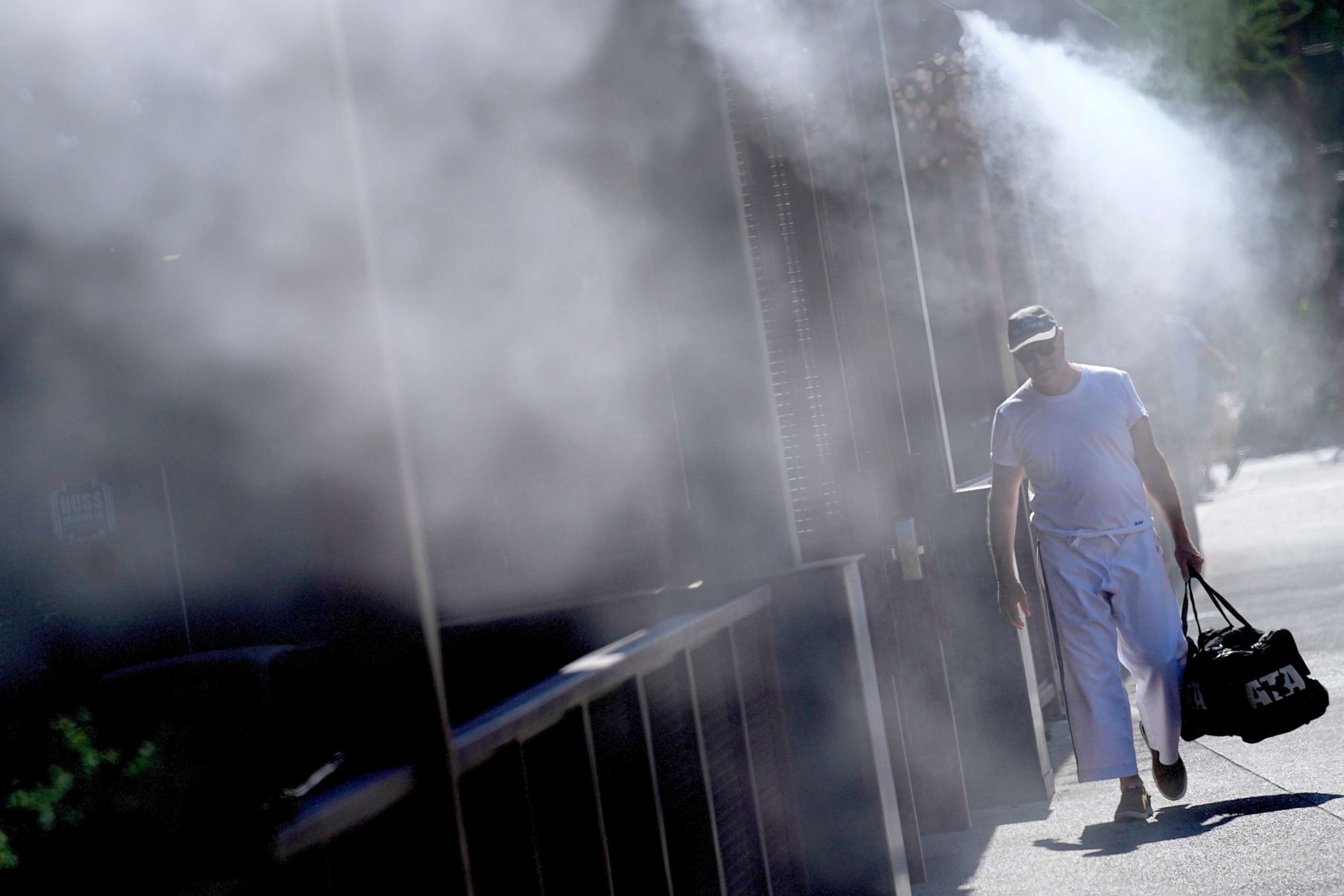 PHOTO: A man walks along a sidewalk under the misters, July 14, 2023, in downtown Phoenix.