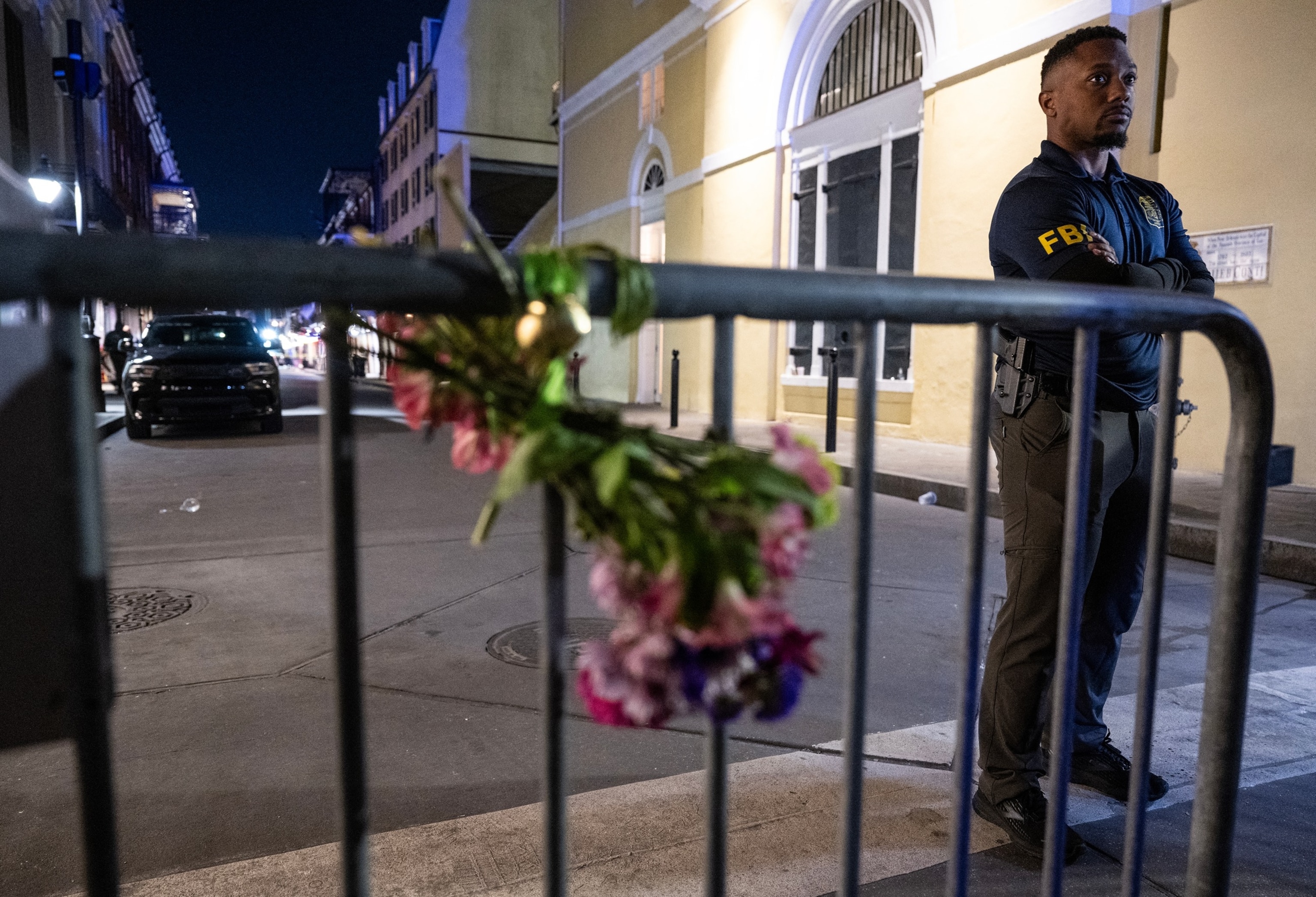 PHOTO: A member of the FBI looks on near a bouquet of flowers tied to a fence, a block from Bourbon Street, after at least 14 people were killed during a terrorist attack, January 1, 2025, in New Orleans, Louisiana.